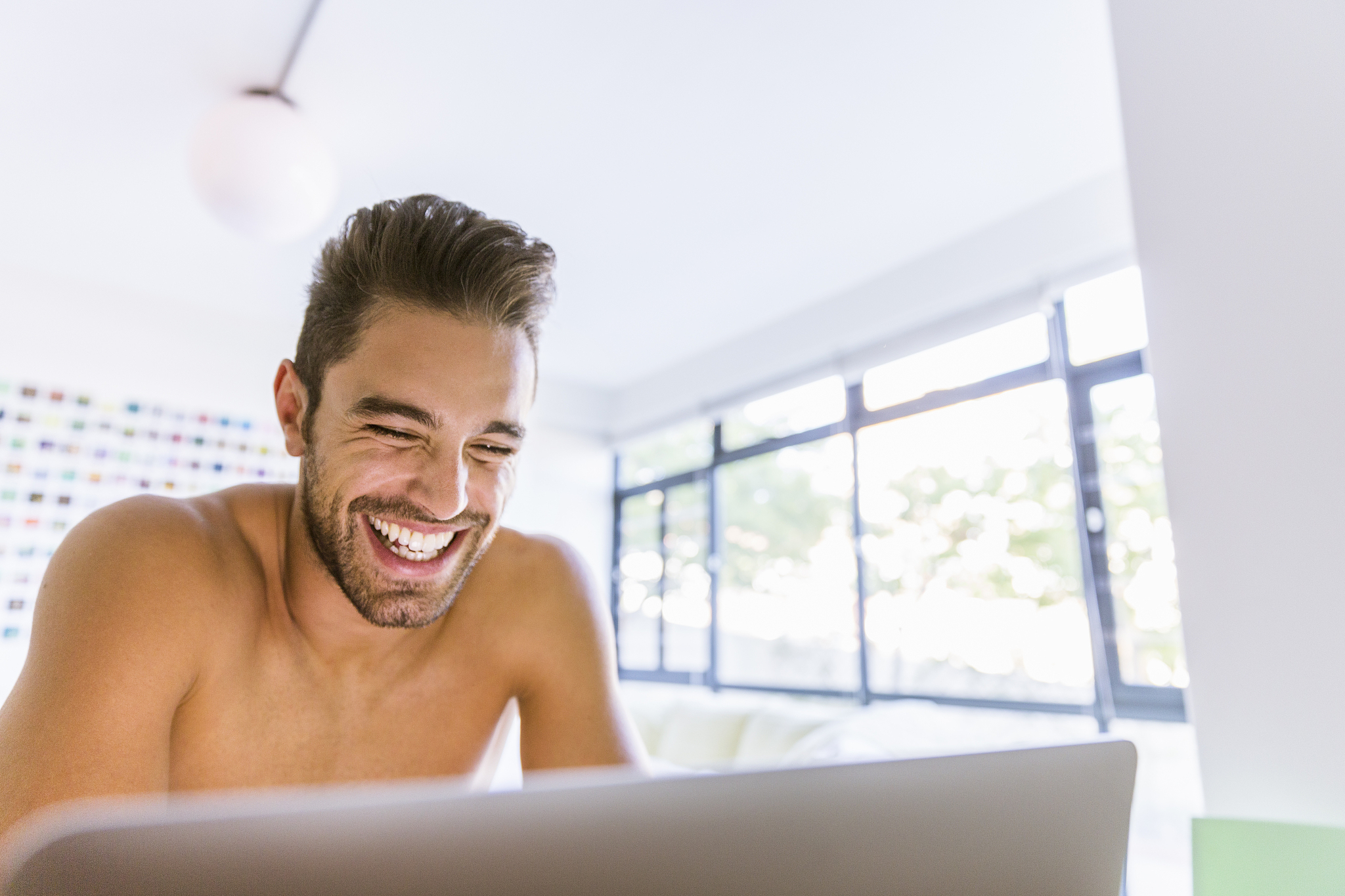 man laughing while using laptop