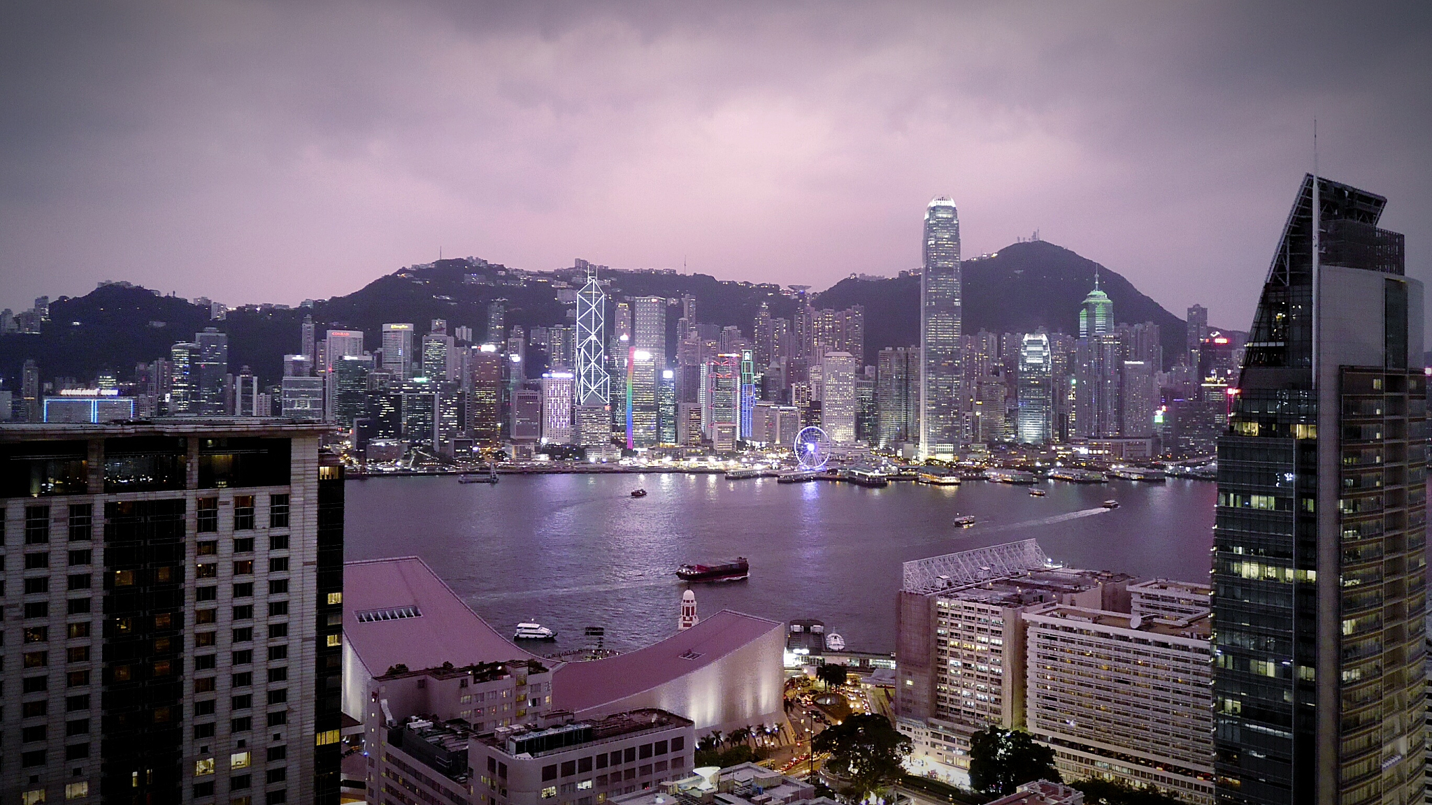 buildings and river at victoria harbour against sky at dusk