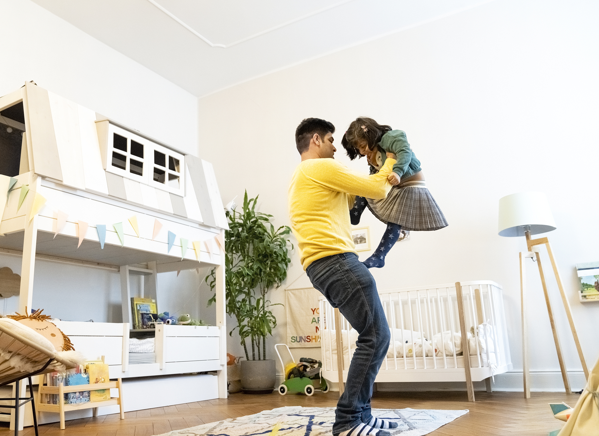 man carrying daughter in bedroom at home