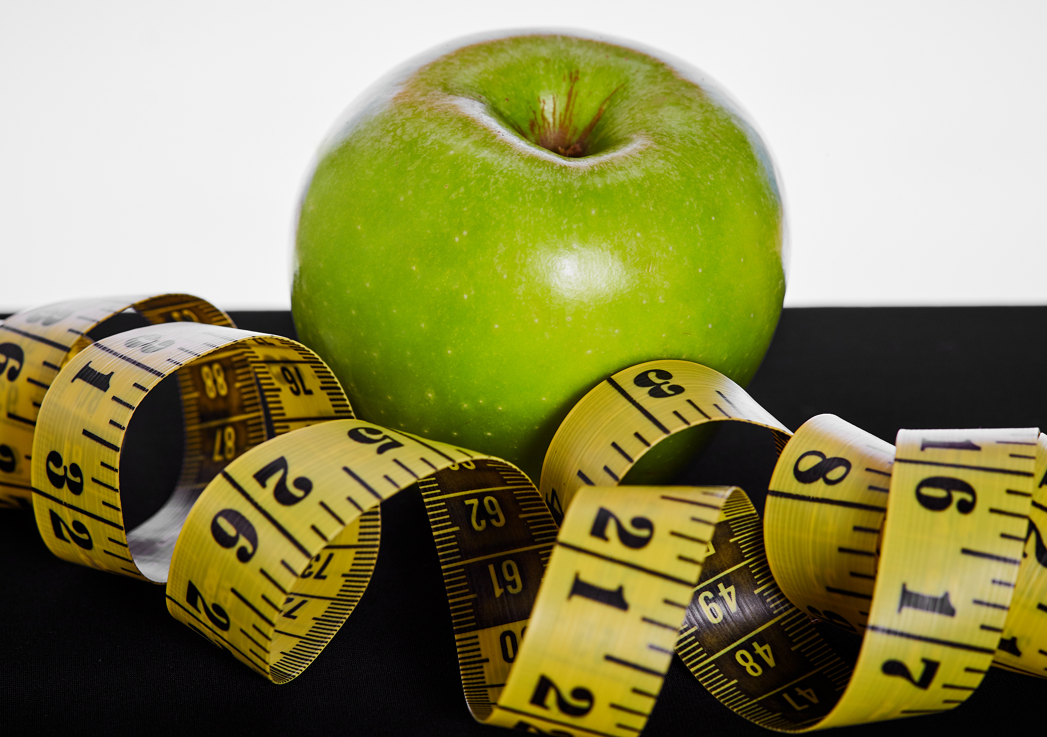 tape measure winds round green apple