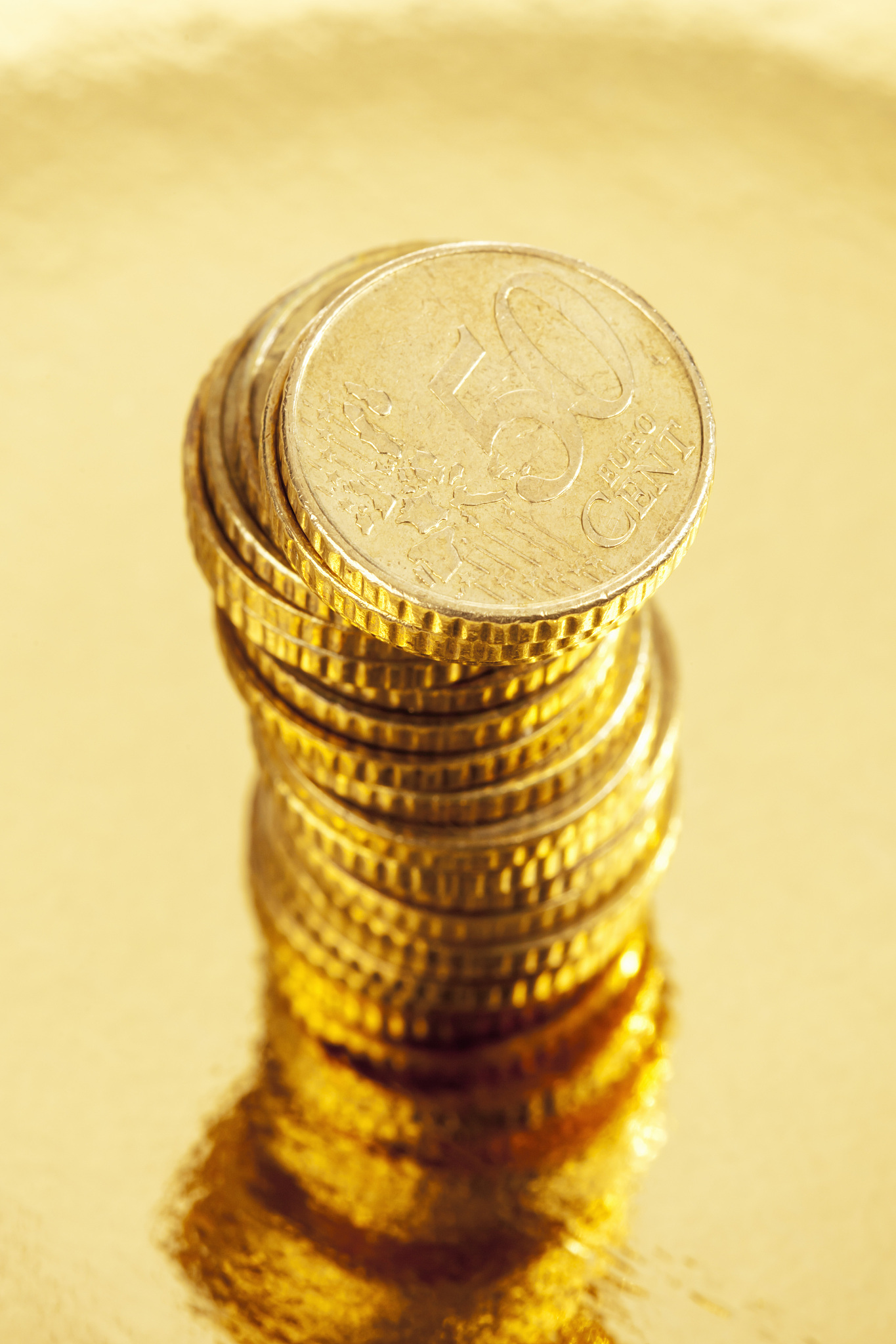 pile of fifty cent euro coins on golden background