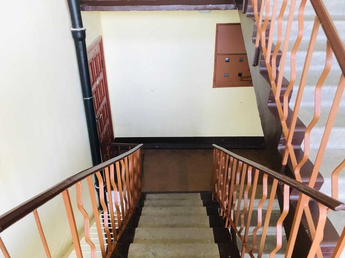 用一段话描写：大厅两侧矗立着两条优雅的L型楼梯上面铺上了精致的红地毯用于通往二楼连廊。