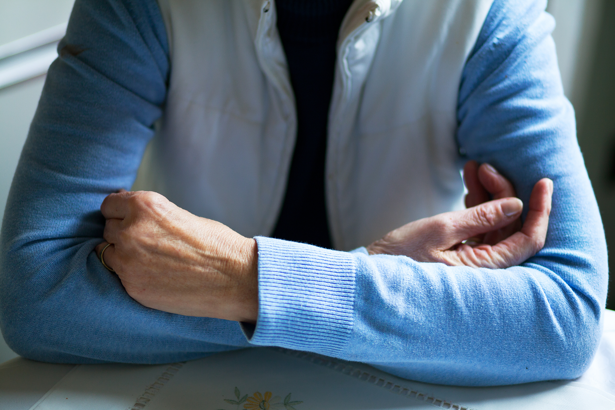 crossed arms of senior on table
