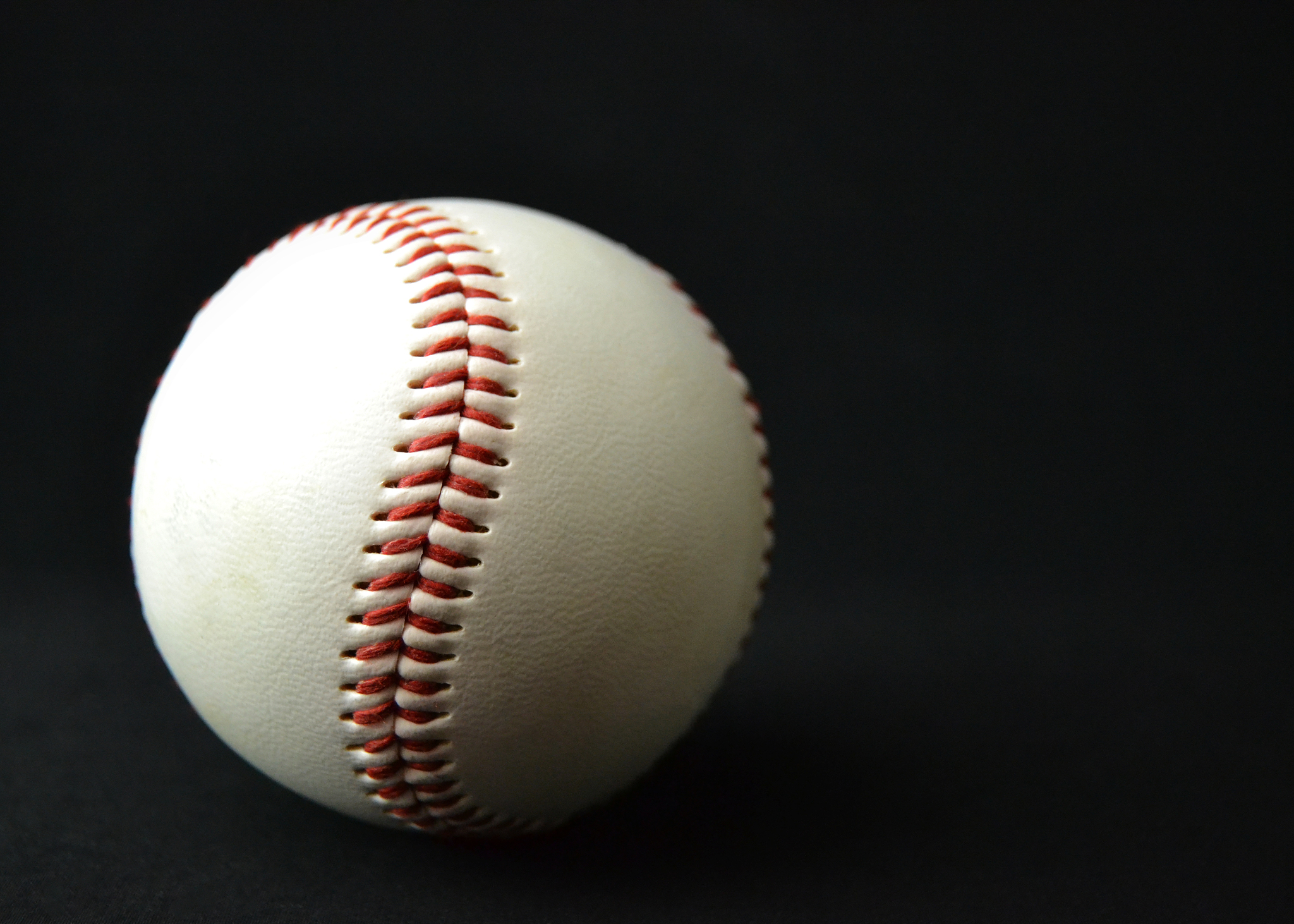 lightly used baseball against black background with dramatic lig