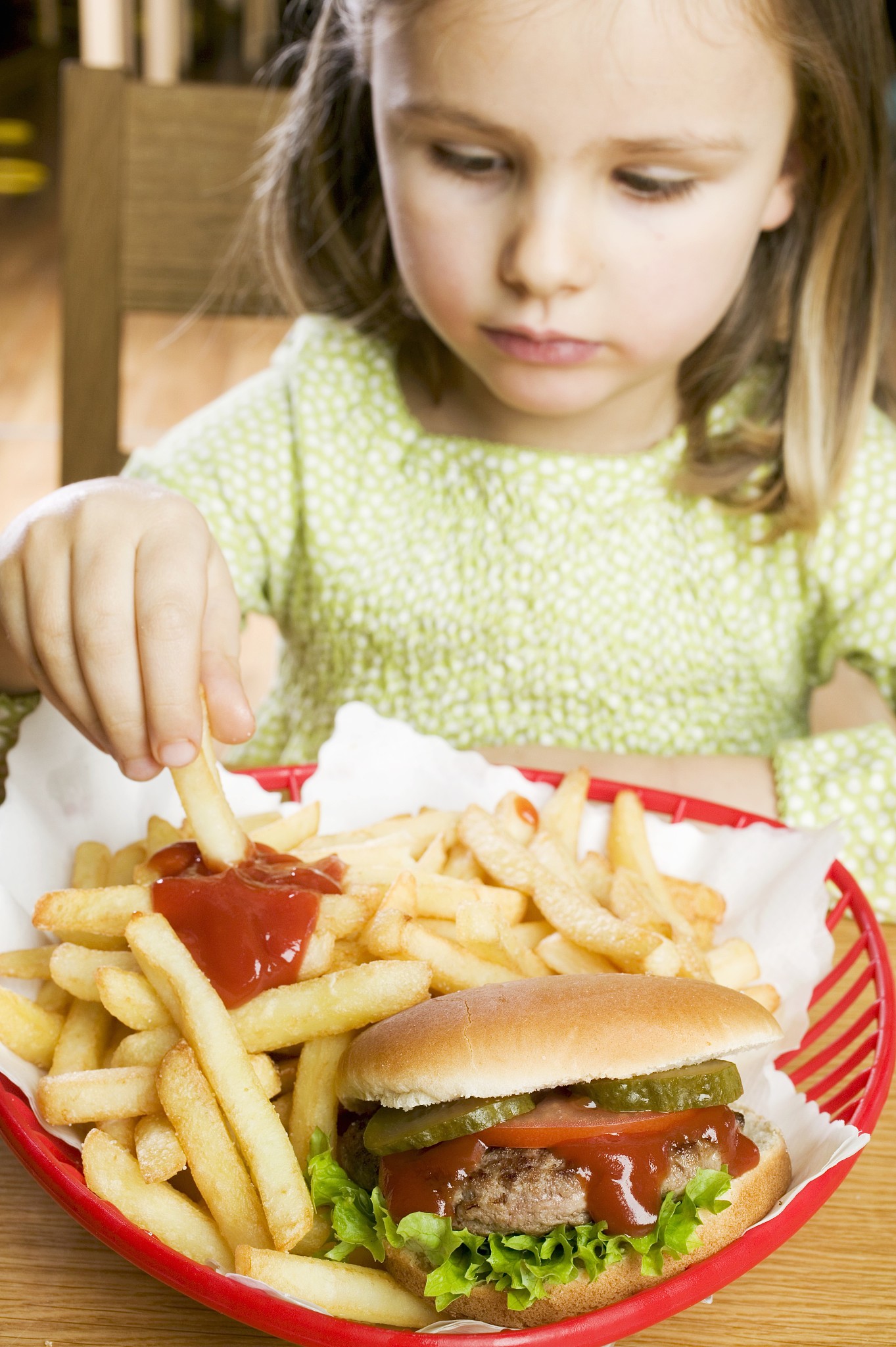 girl eating chips with ketchup and hamburger