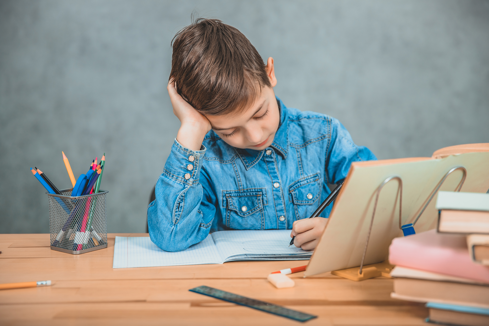 young concentrated school kid in blue jeans t-shirt writing sitt