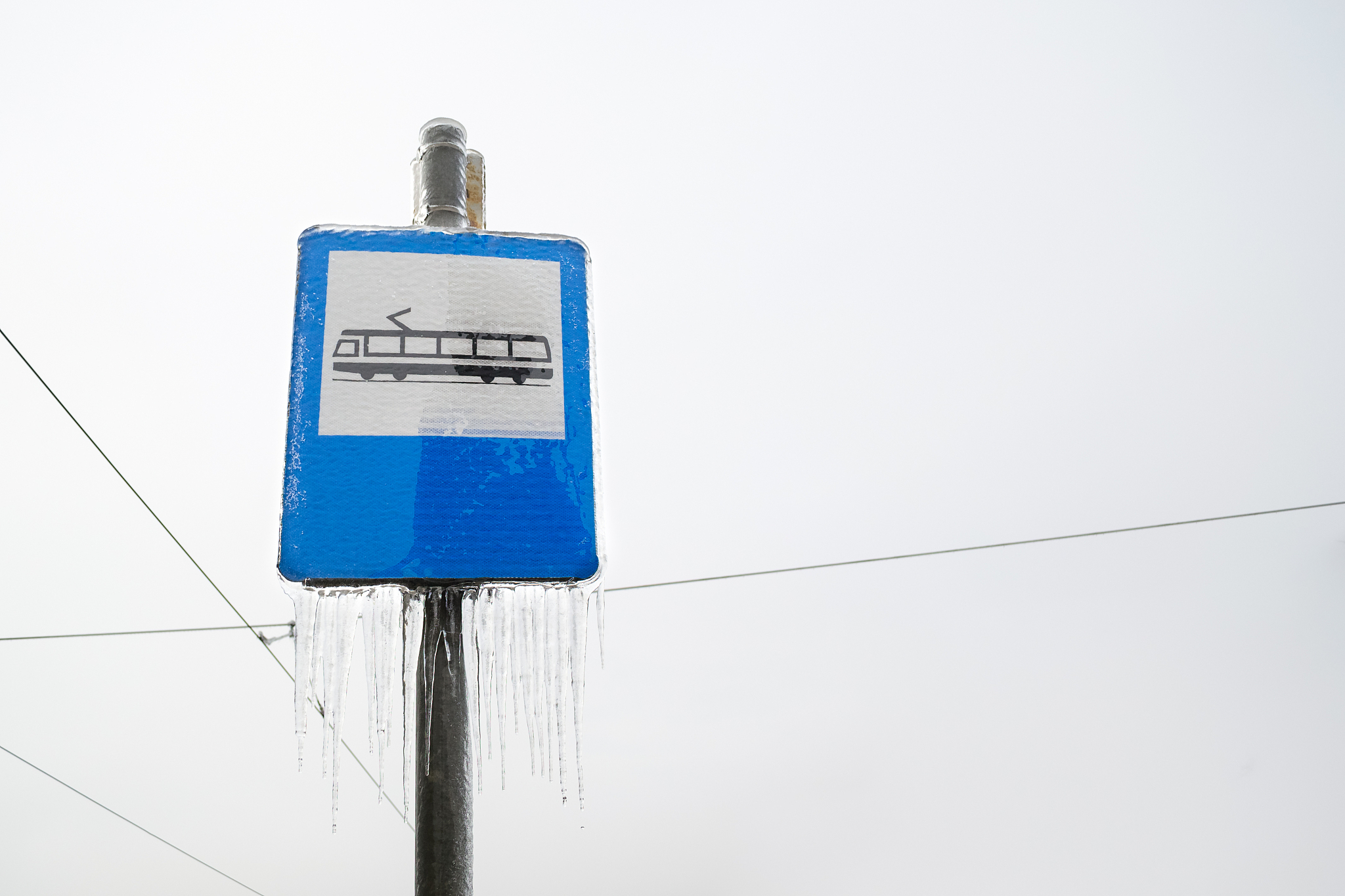 tram station sign with icicles hanging from it, on blue backgrou