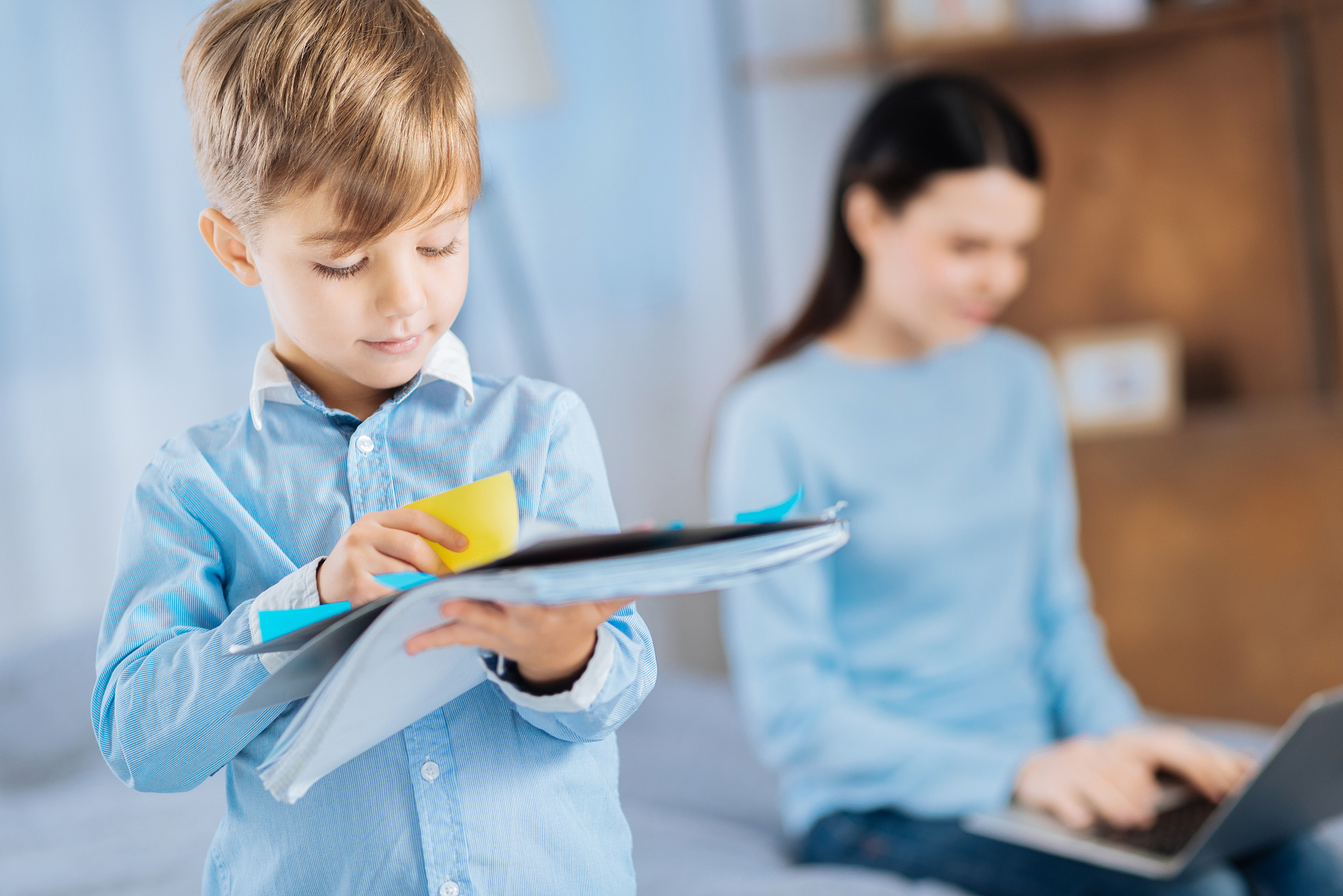 little boy sticking memos to notebook page