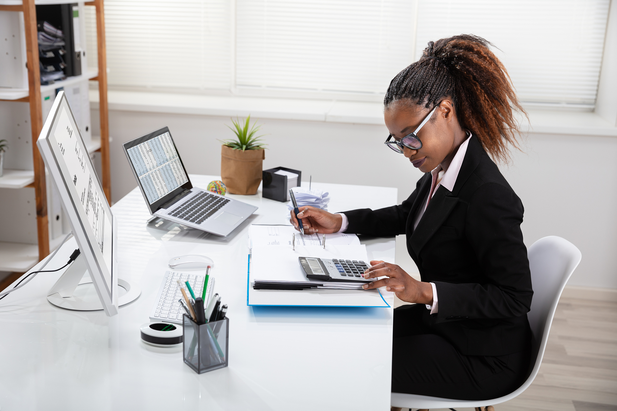 smiling businesswoman calculating invoice on computer
