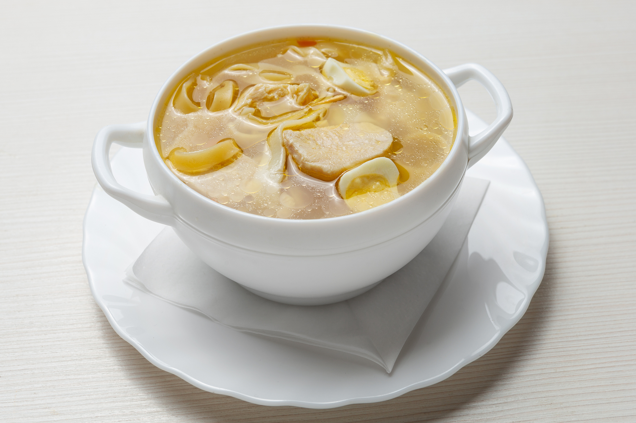 noodle soup, with meat and quail eggs, in a white plate