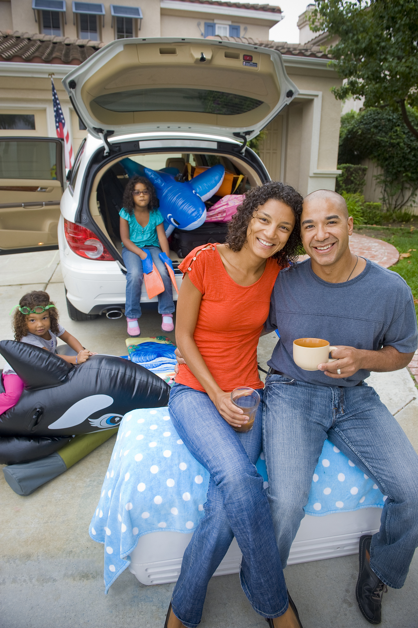 family in their driveway packing for vacation