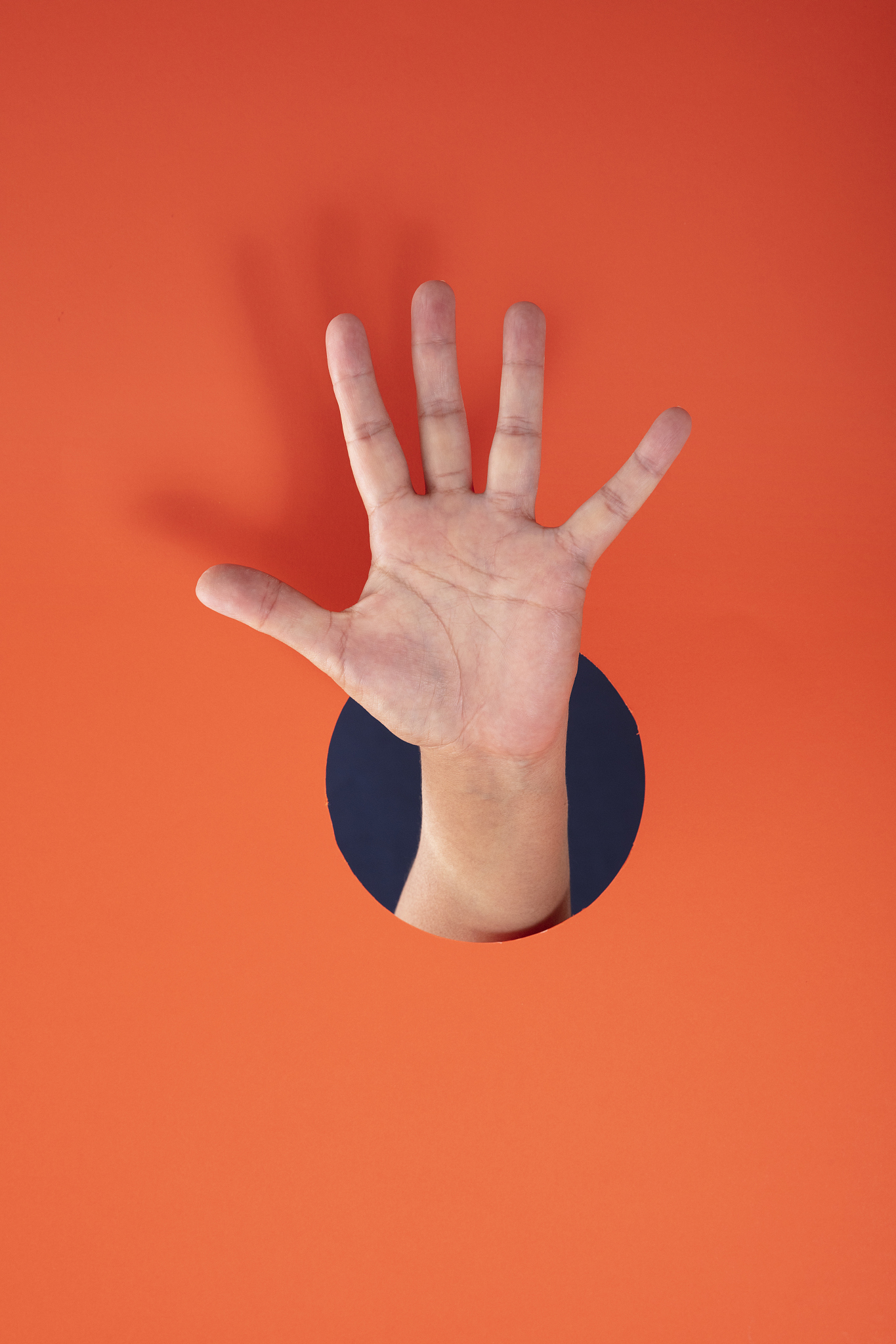 female hand showing number five on orange paper background