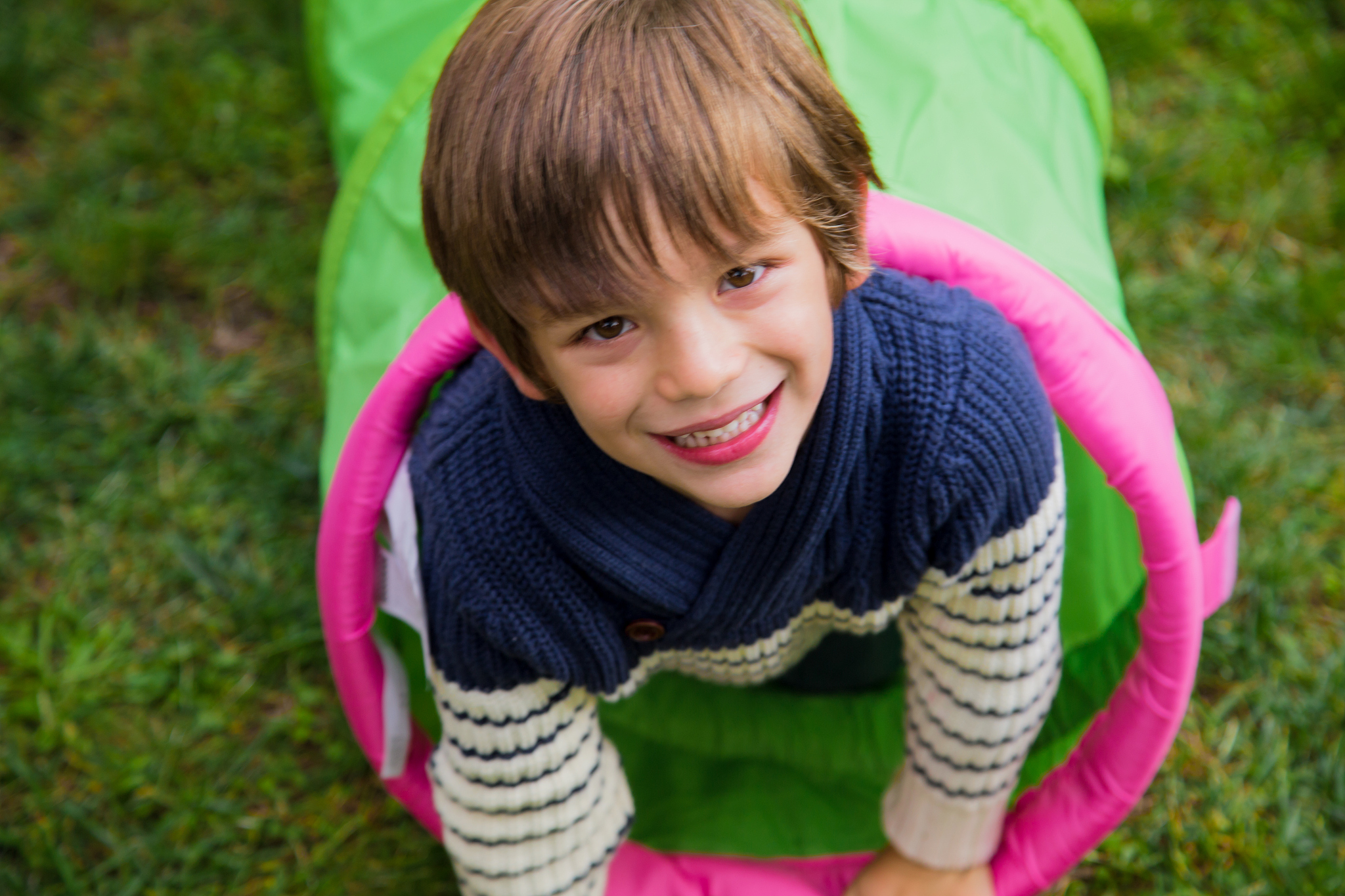 boy kid playing inside a green pipe in the garden.