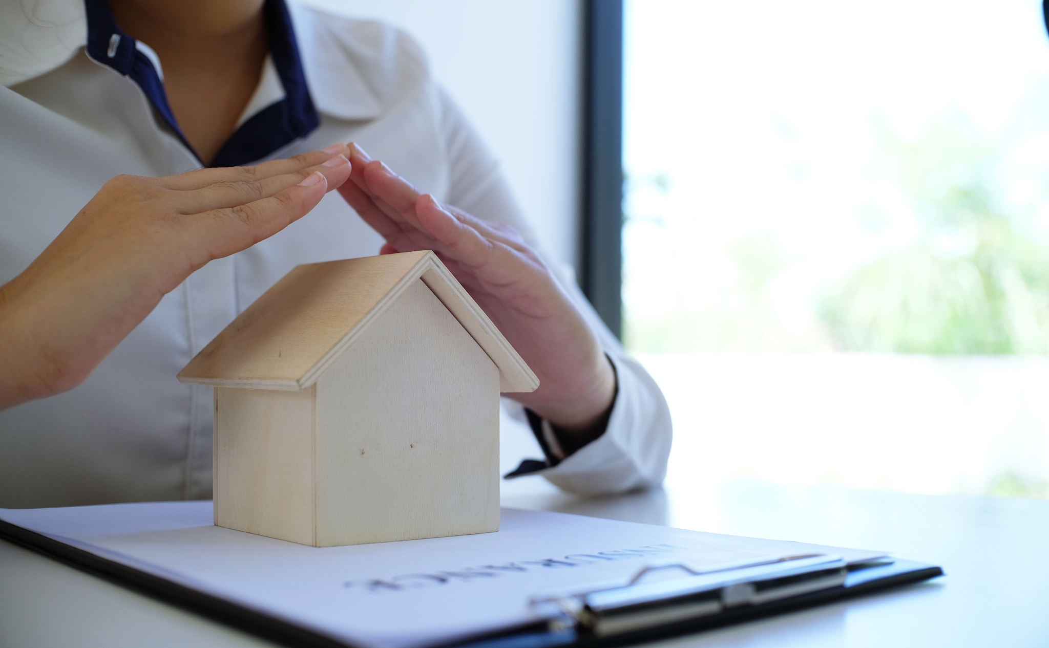 insurance agent protecting with hand over house business concept