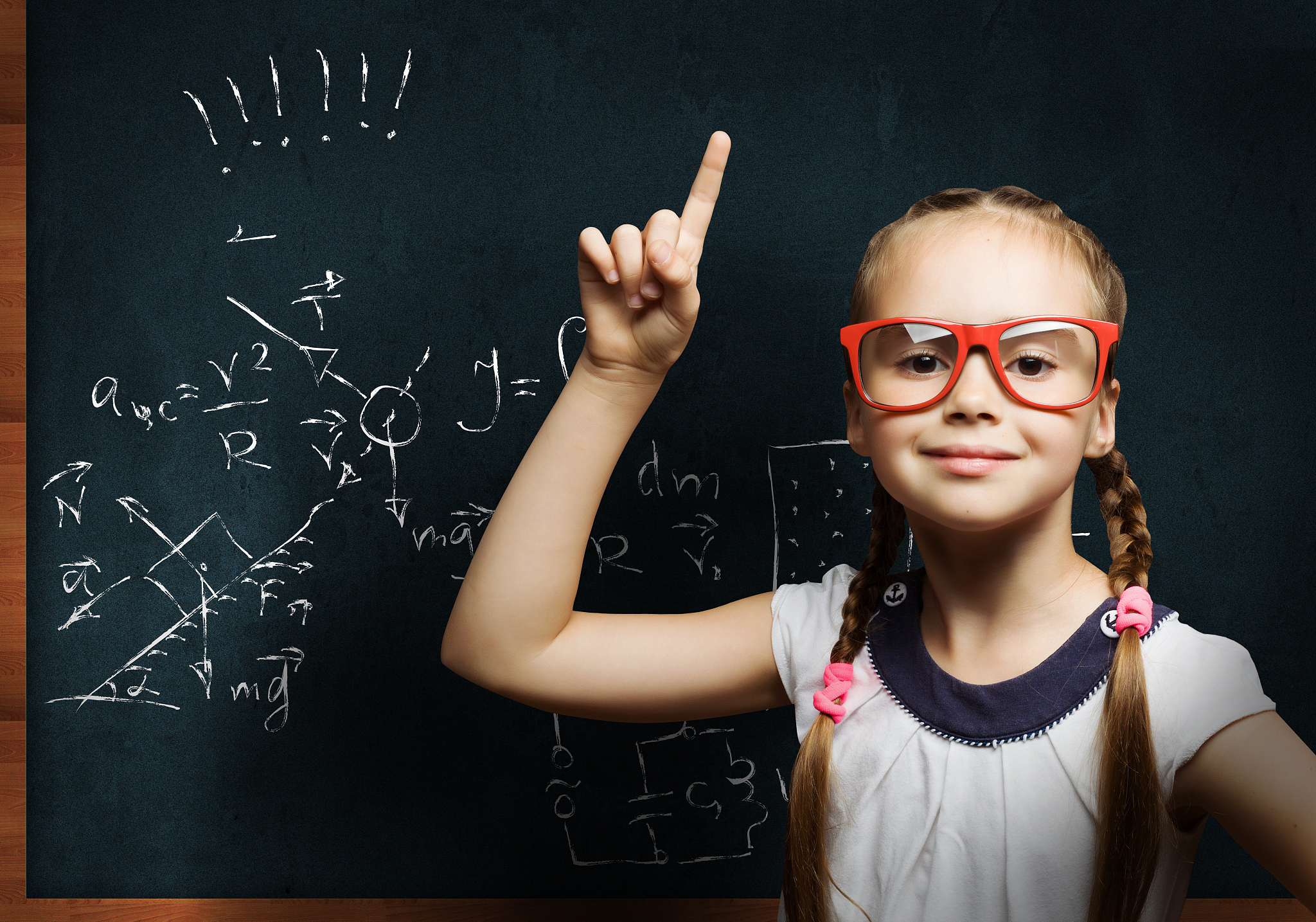 wunderkind. cute school girl in glasses standing at blackboard