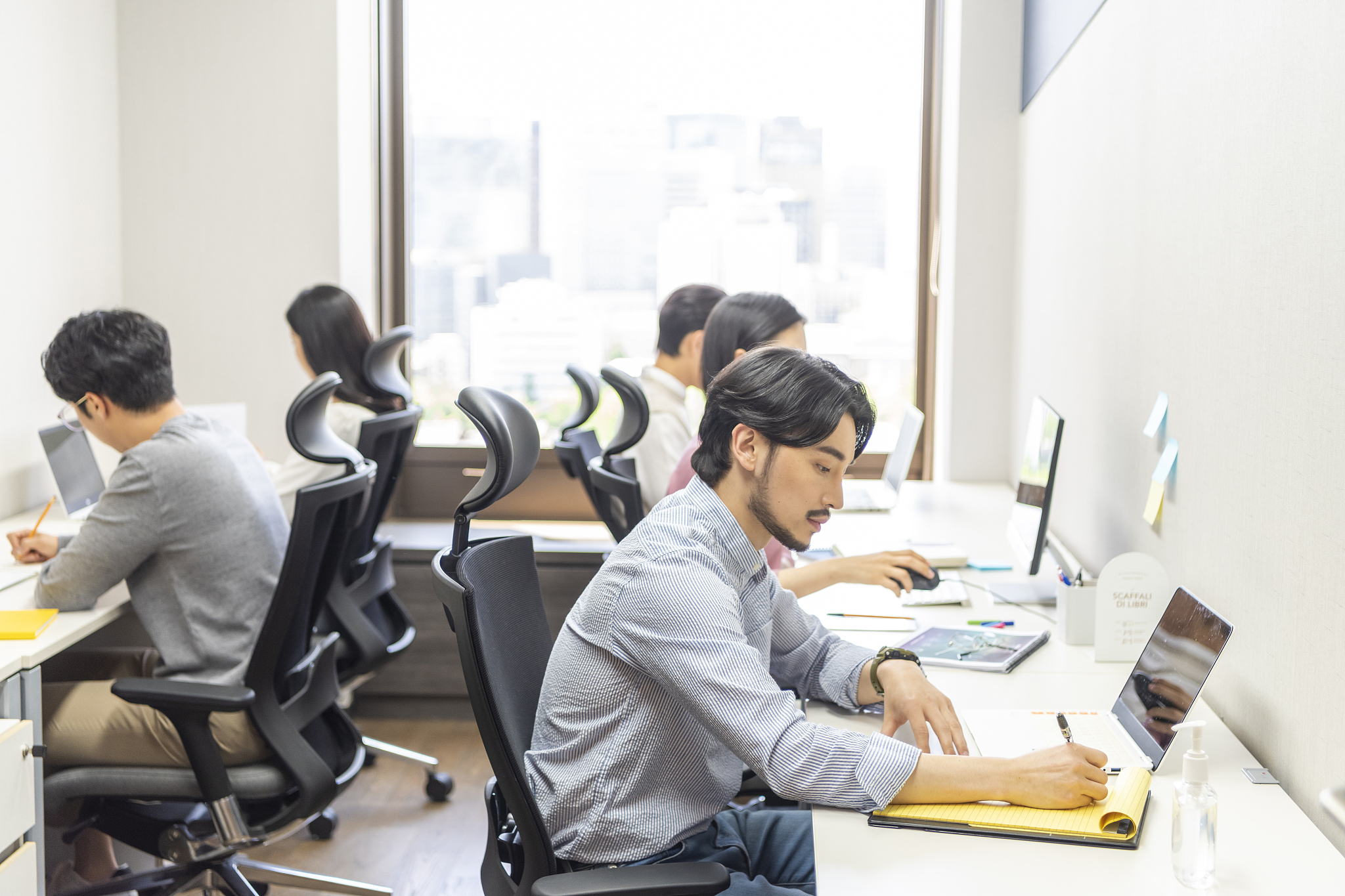 businessmen and businesswomen sitting by desk with laptop workin