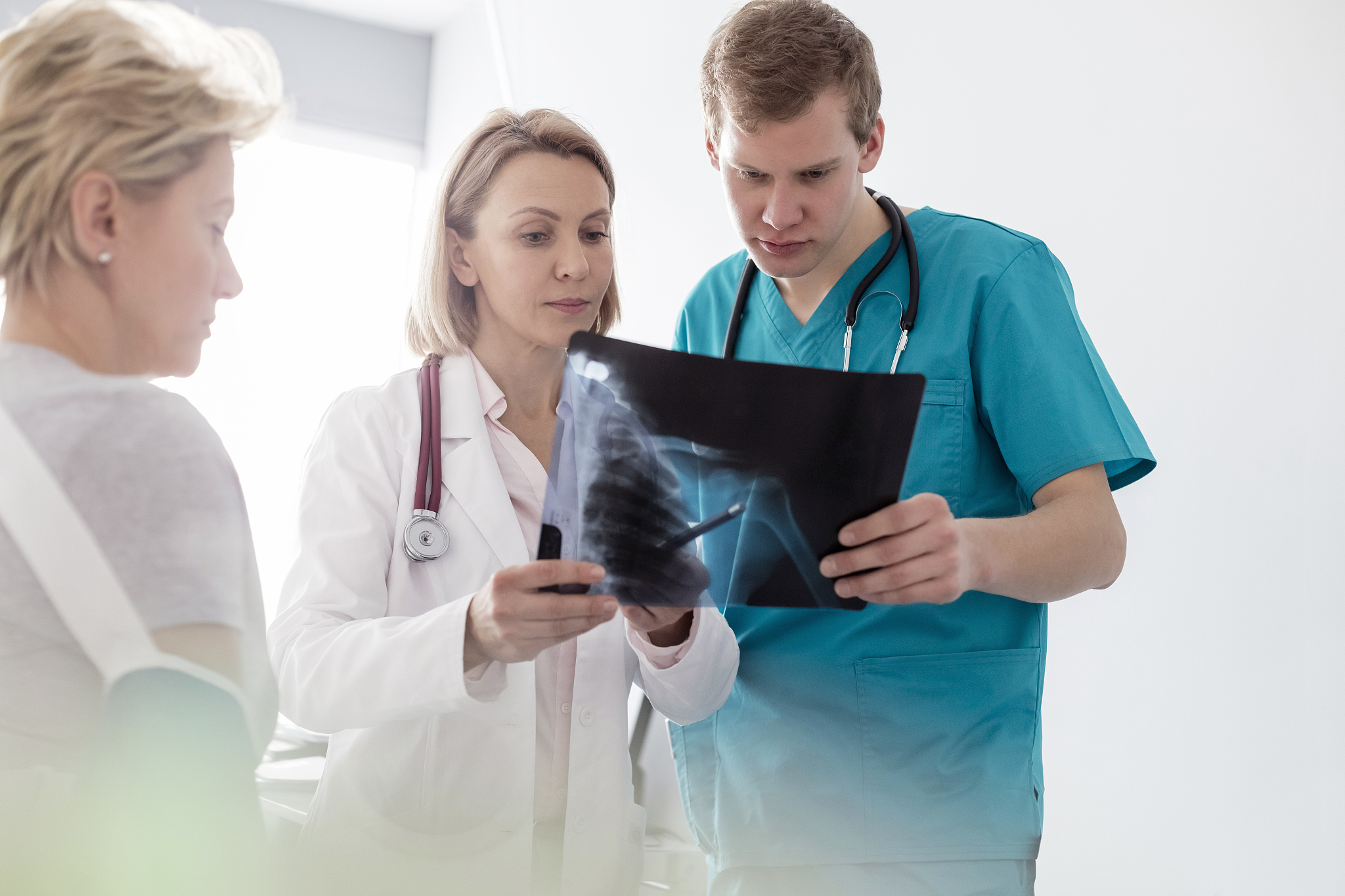 physiotherapist discussing over x-ray to nurse and patient at ho