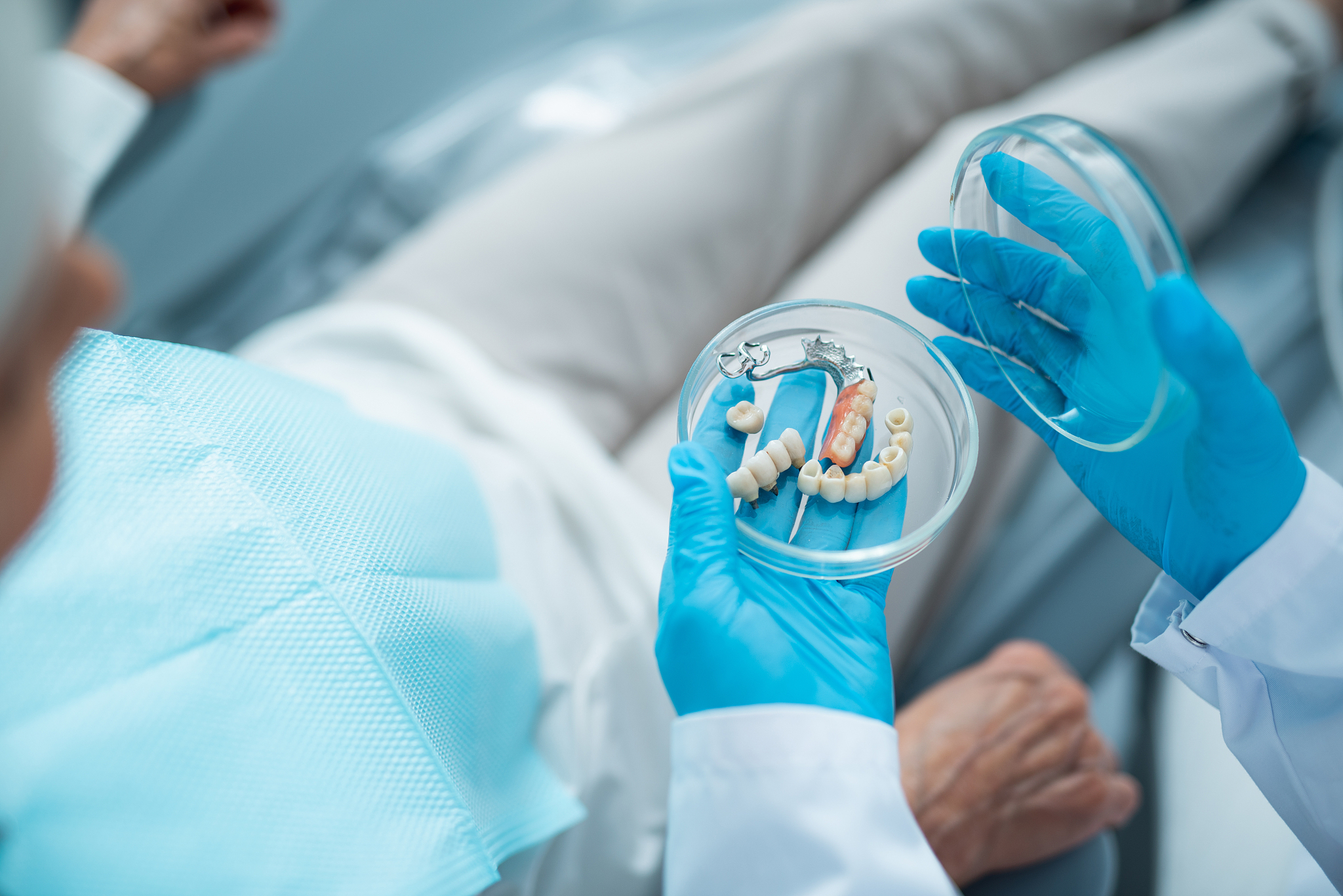 dentist is holding false teeth in clinic