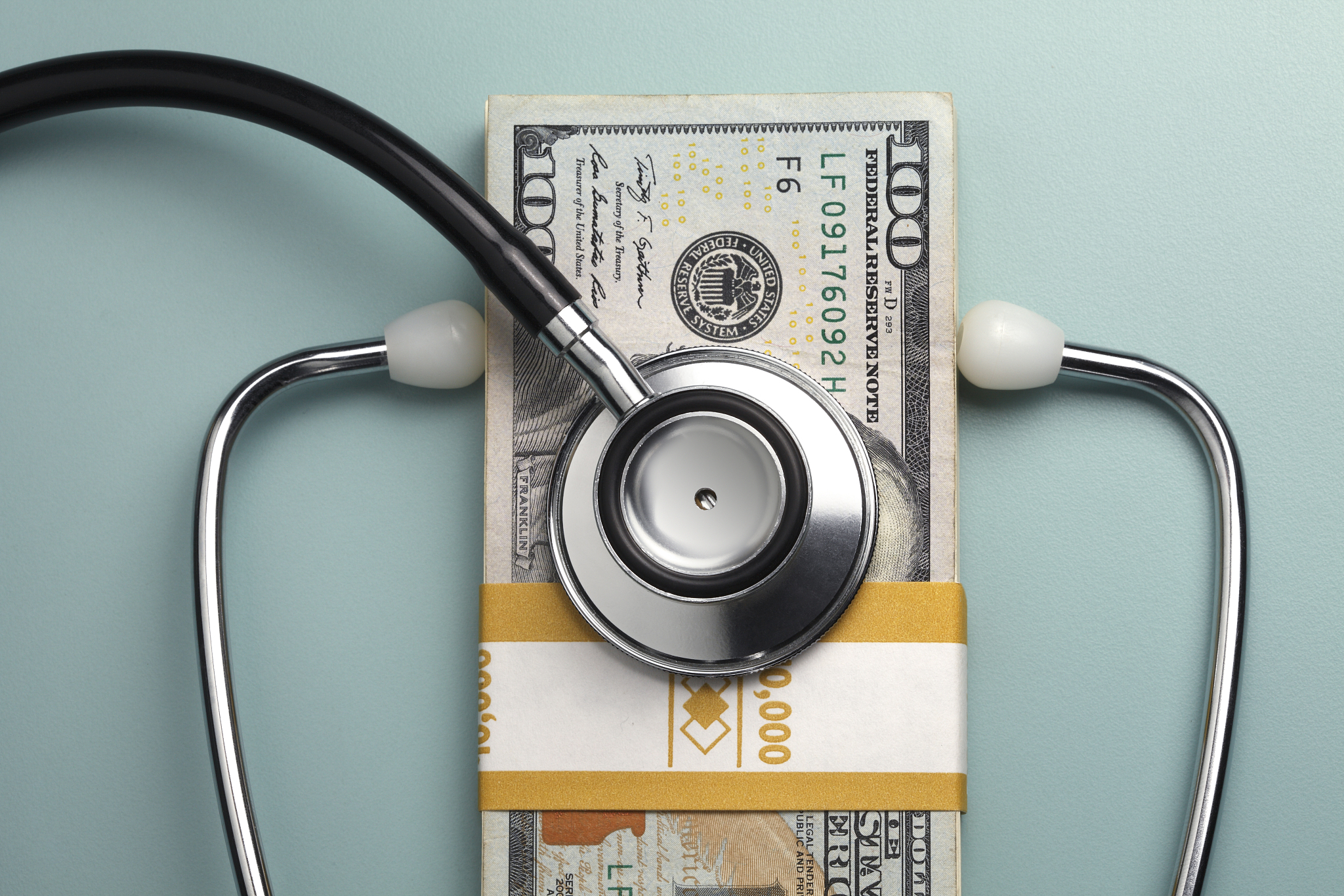 stethoscope on a stack of one hundred dollar bills