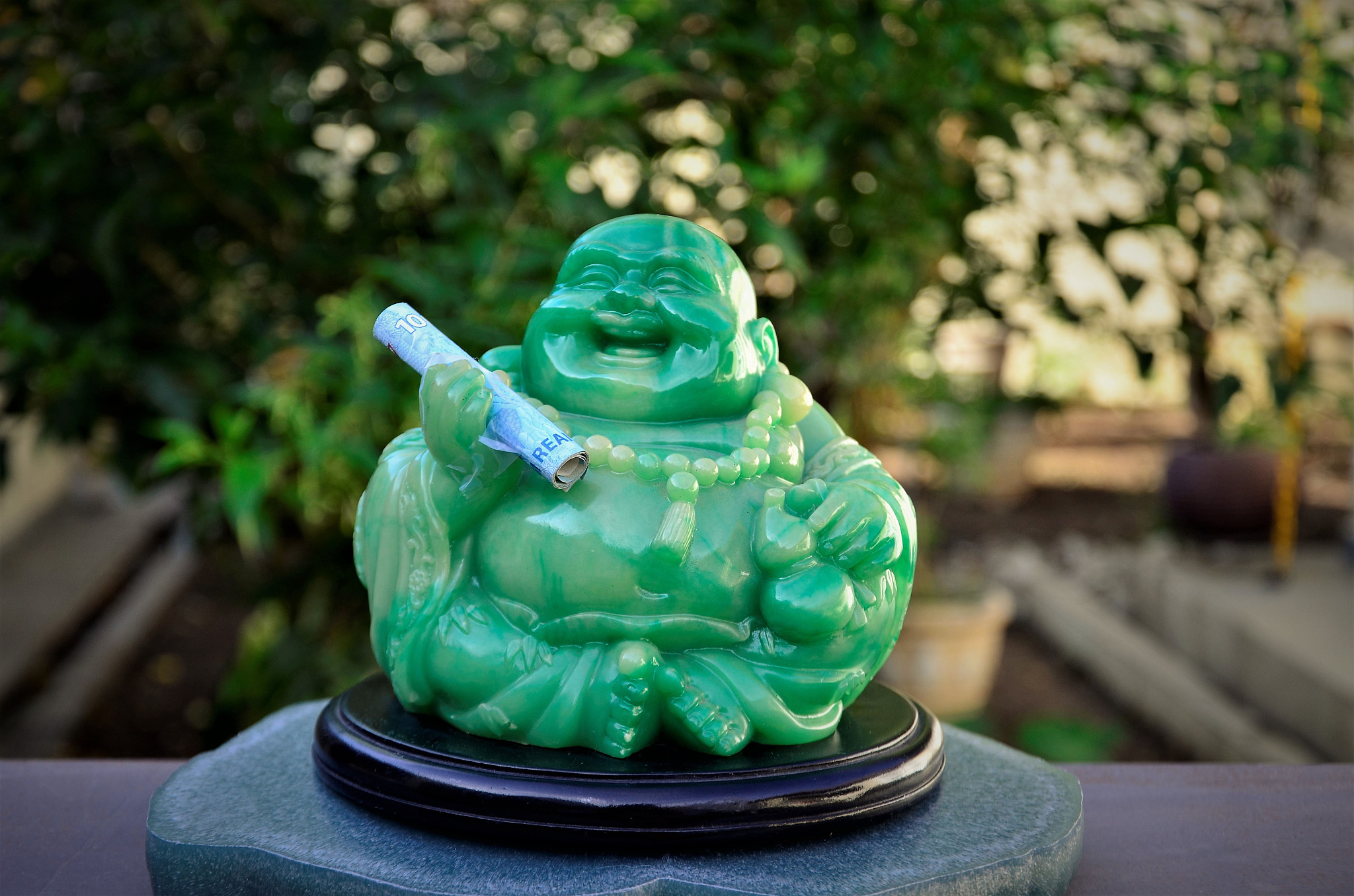 green buddha holding smiling money