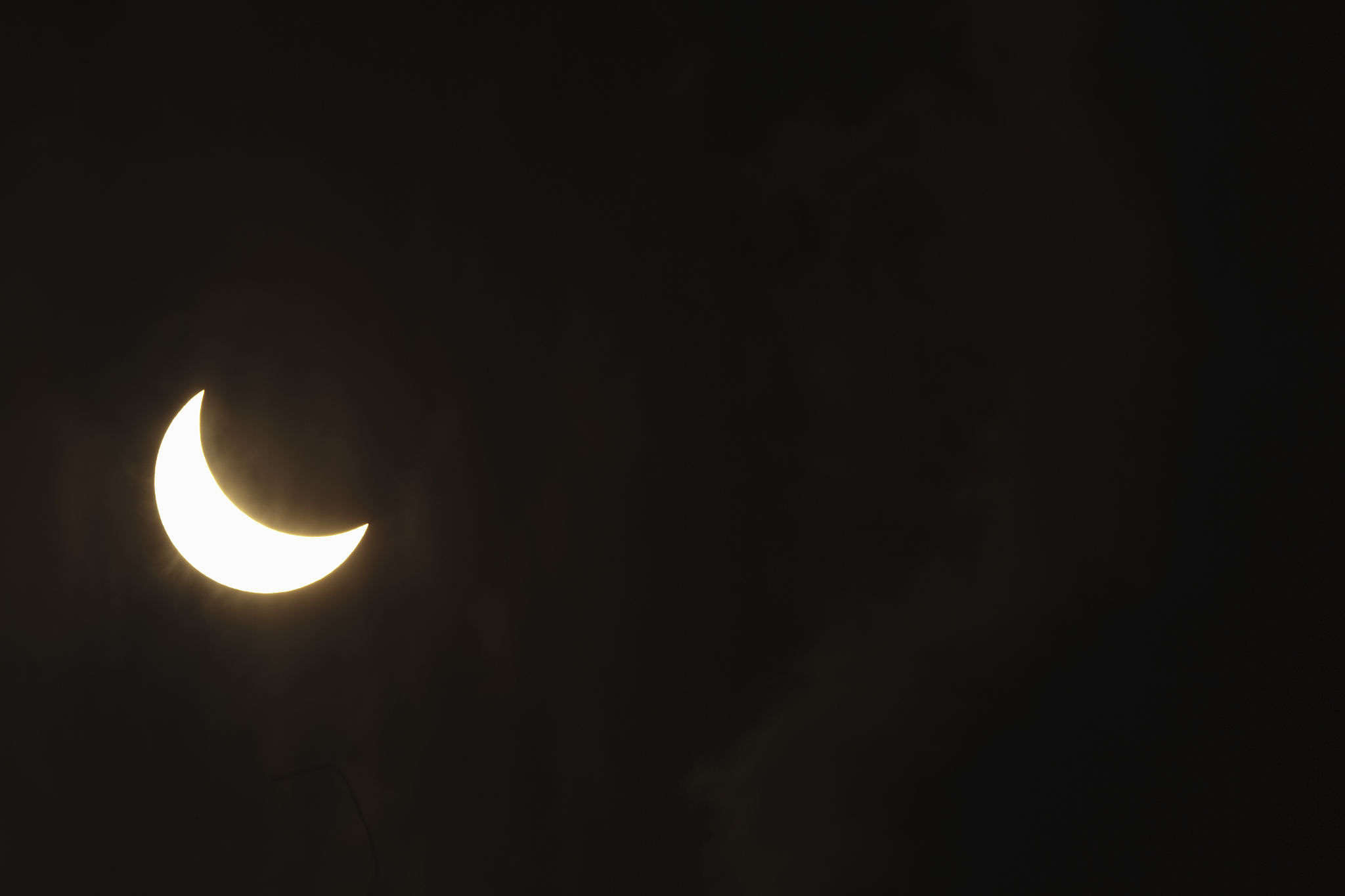 partial solar eclipse through clouds
