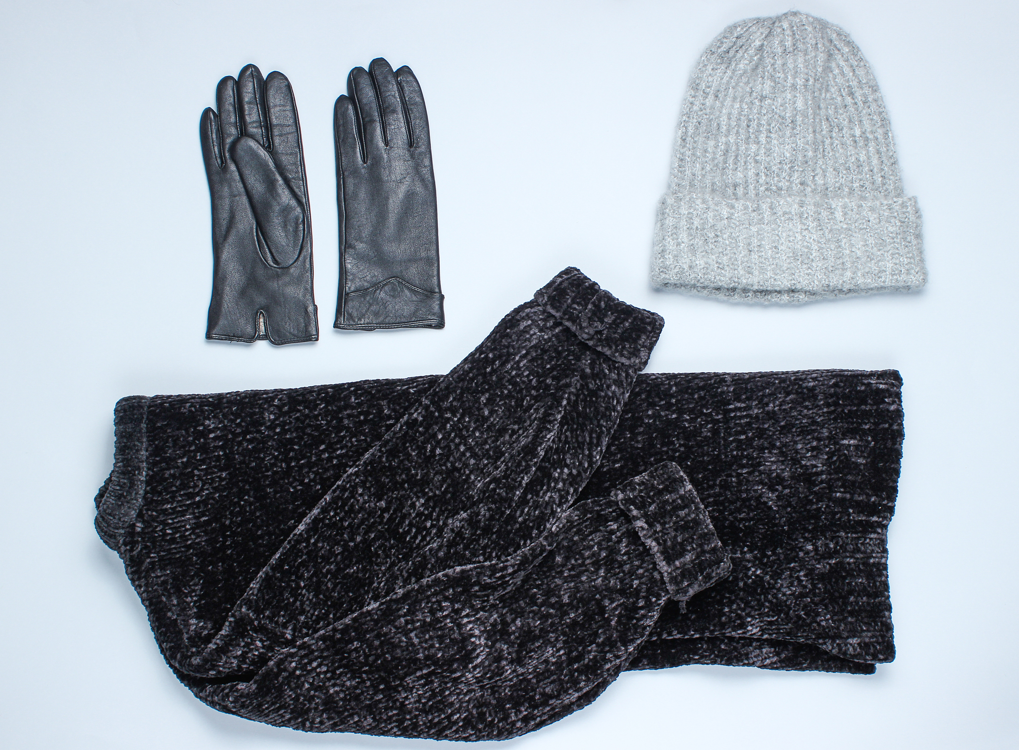 velor black sweater, leather gloves, warm wool hat on a gray bac