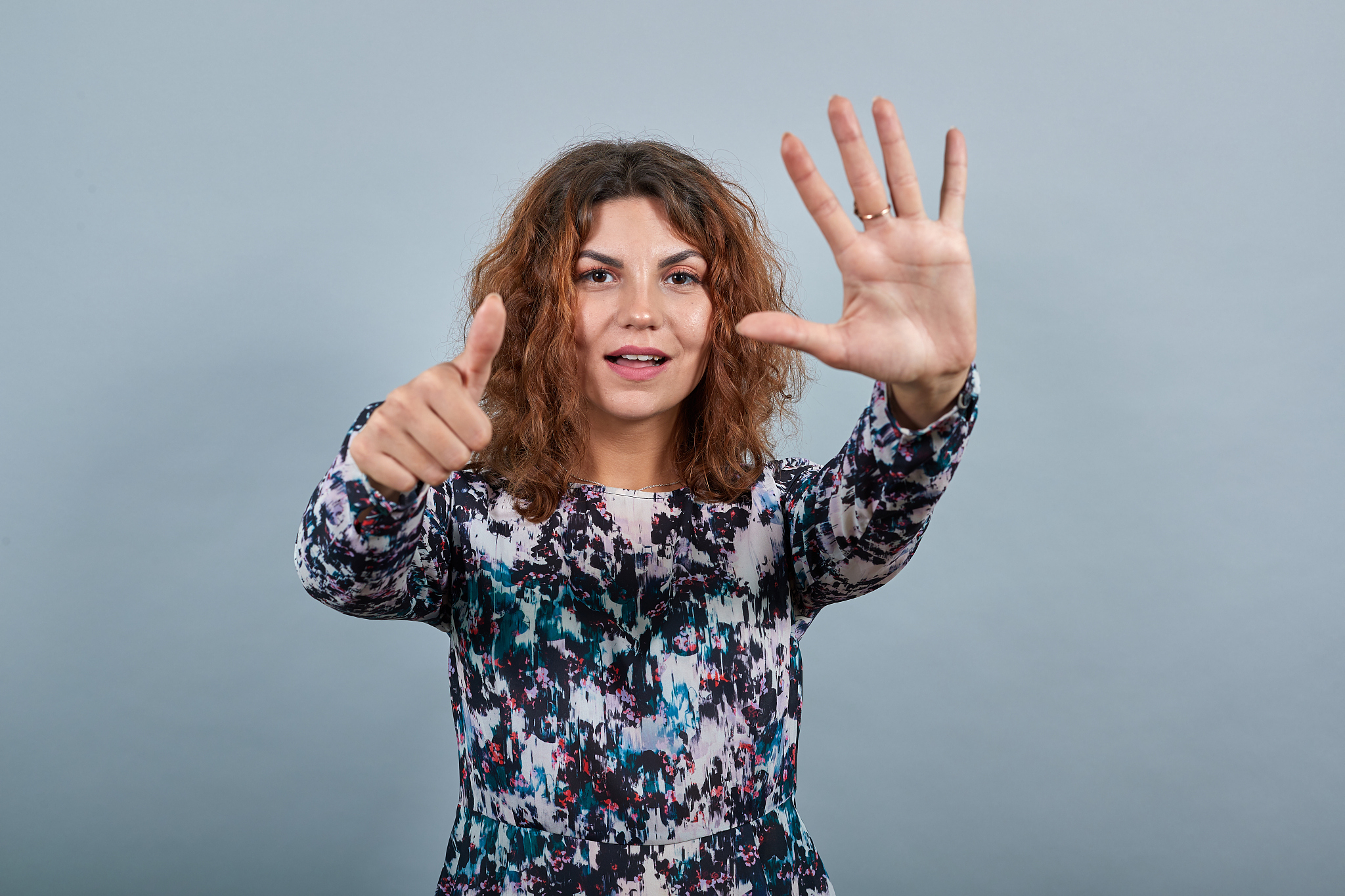 cheerful charming young lady showing six fingers at camera, smil