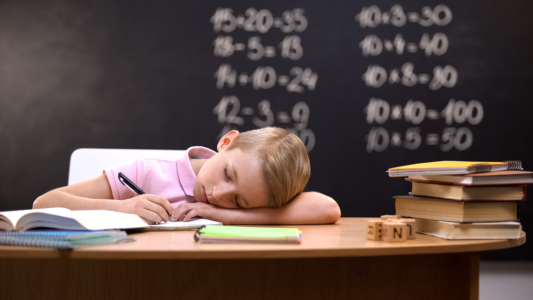 tired schoolboy napping on desk, fallen asleep while preparing a