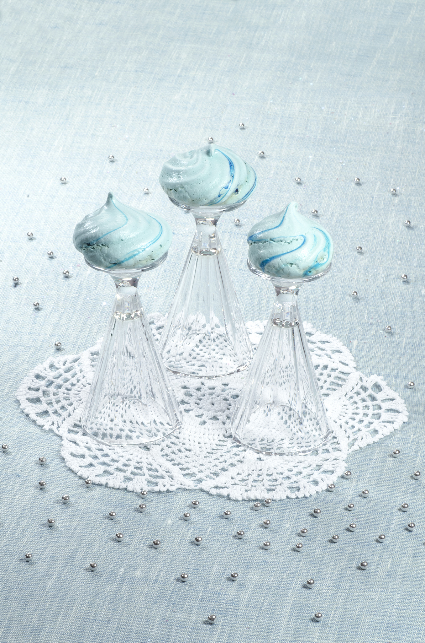three homemade meringue shaped domes on crystal wine-glasses