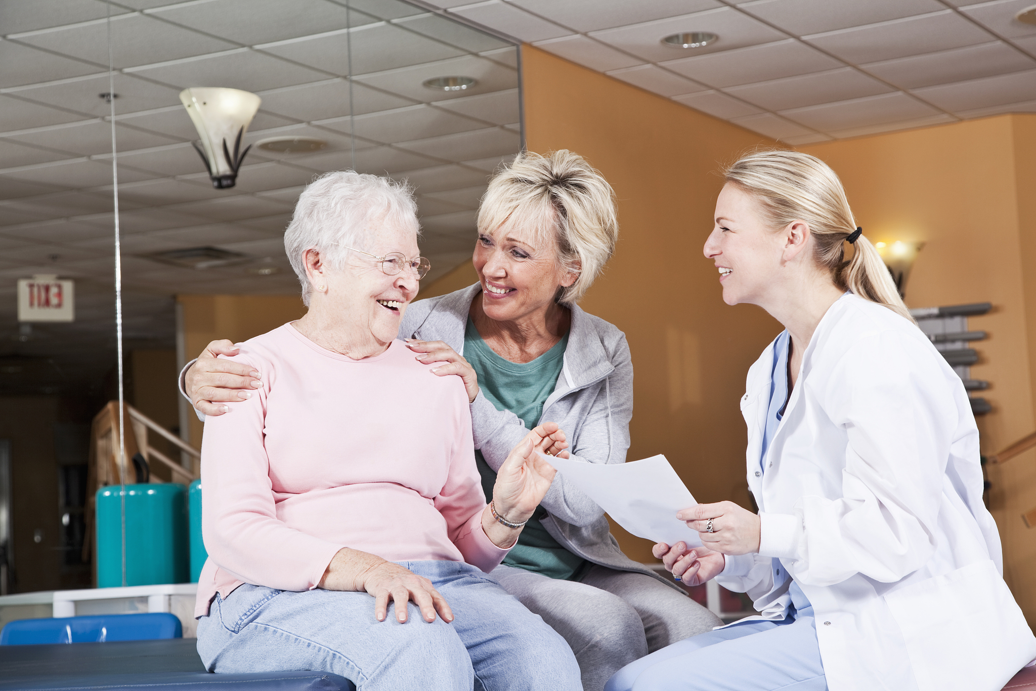 senior woman and adult daughter talking to physical therapist