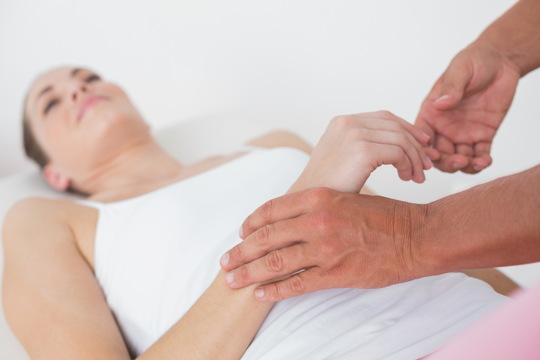 physiotherapist examining her patient hand in medical office