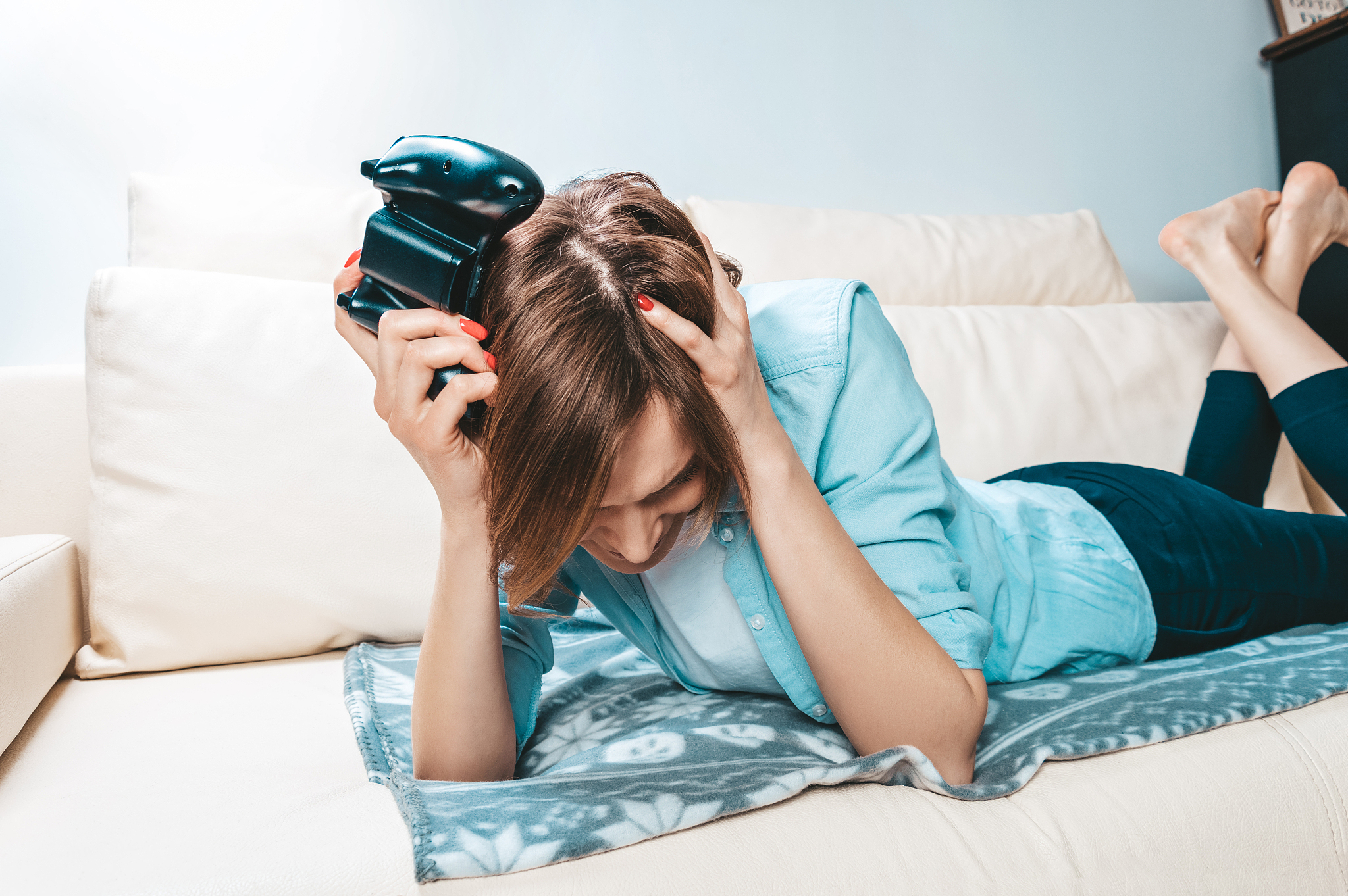 the girl with the joystick in her hands lies on the couch upset 