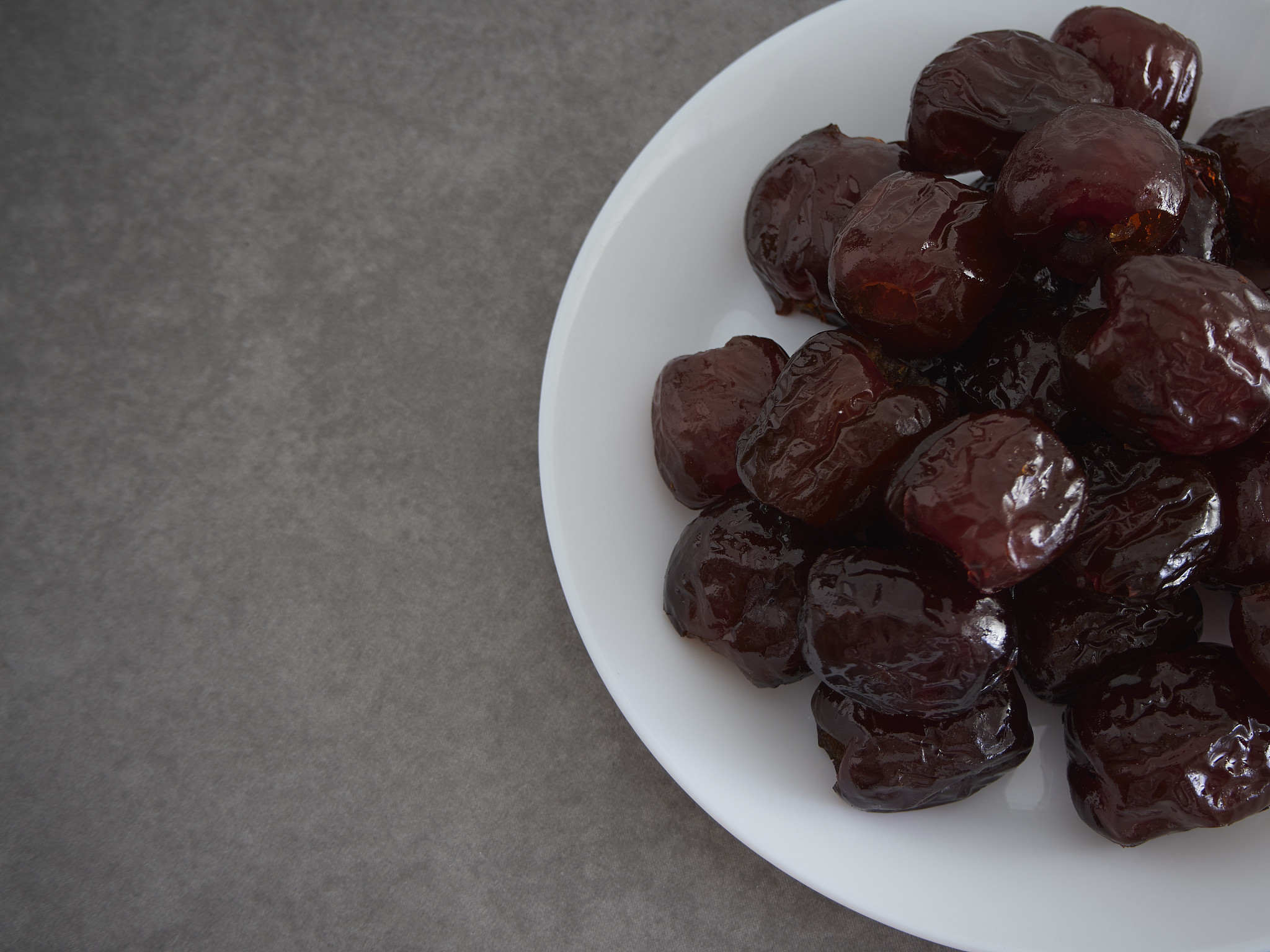 jujube sweet dried fruit on a white plate on a gray marble table