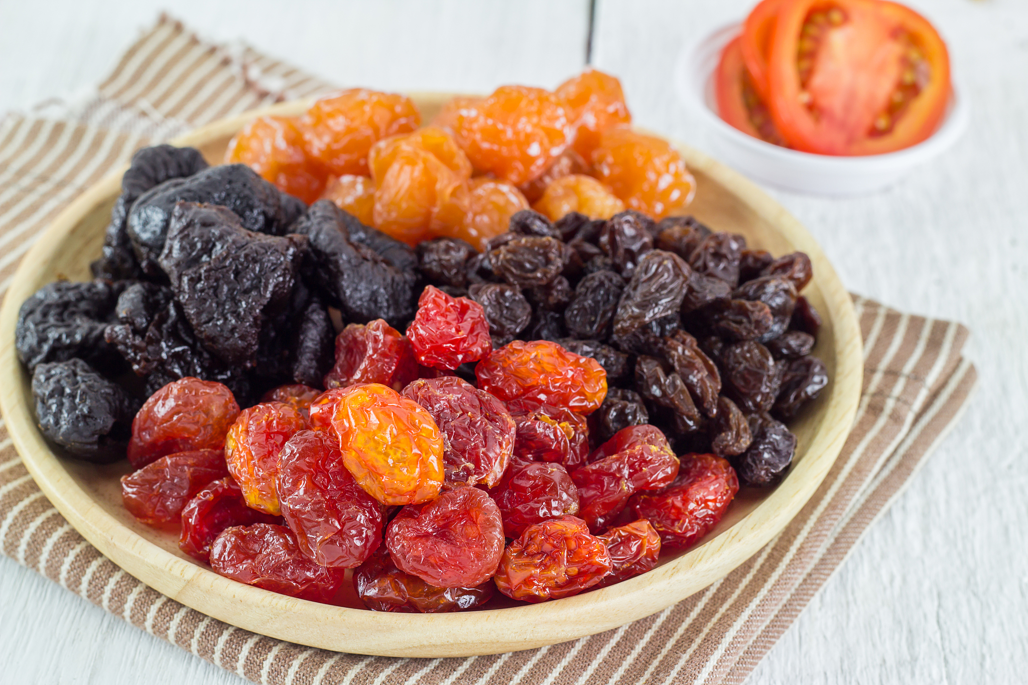 heap of various dried fruits in brown wooden plate