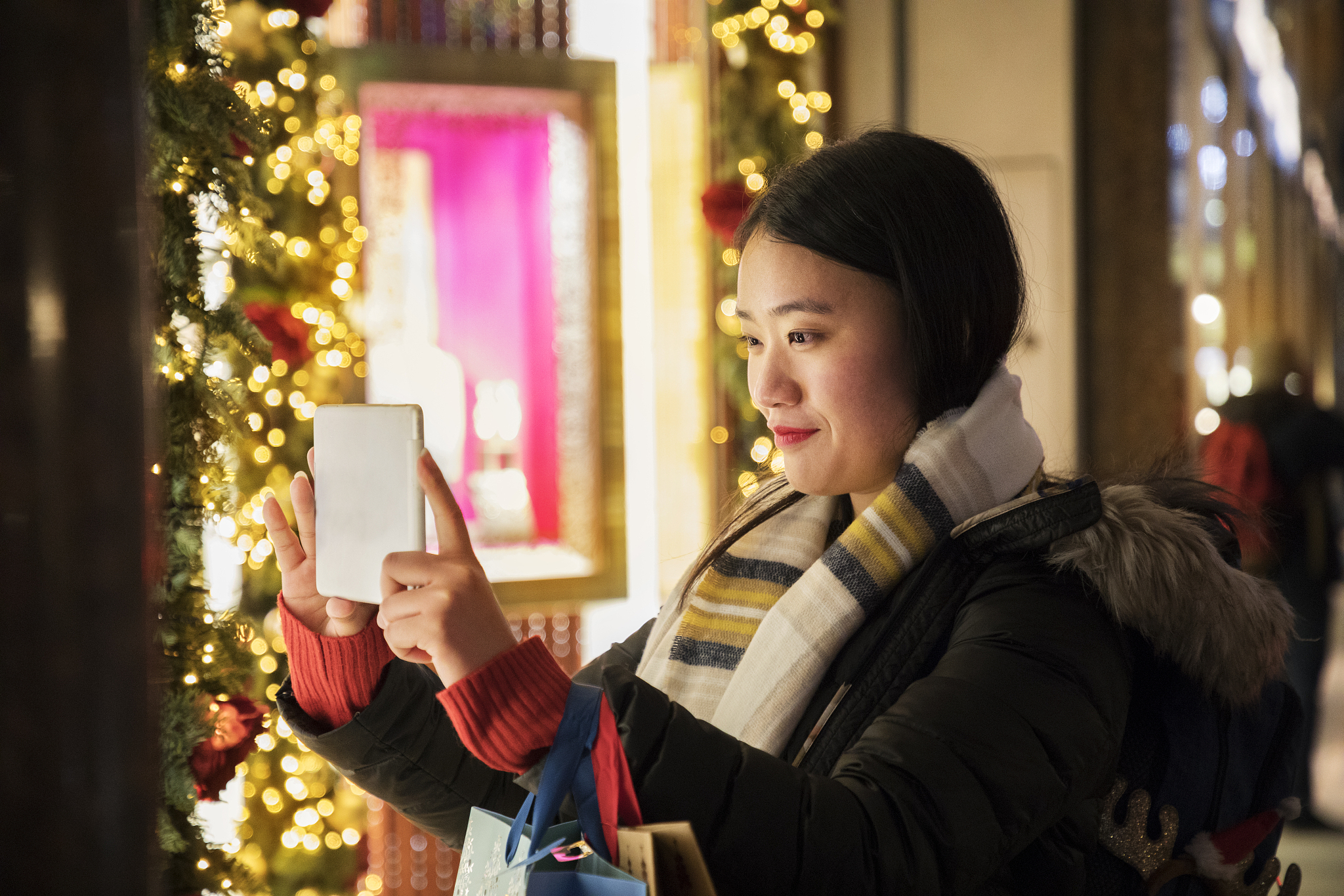 asian woman films shop window, using digital tablet.