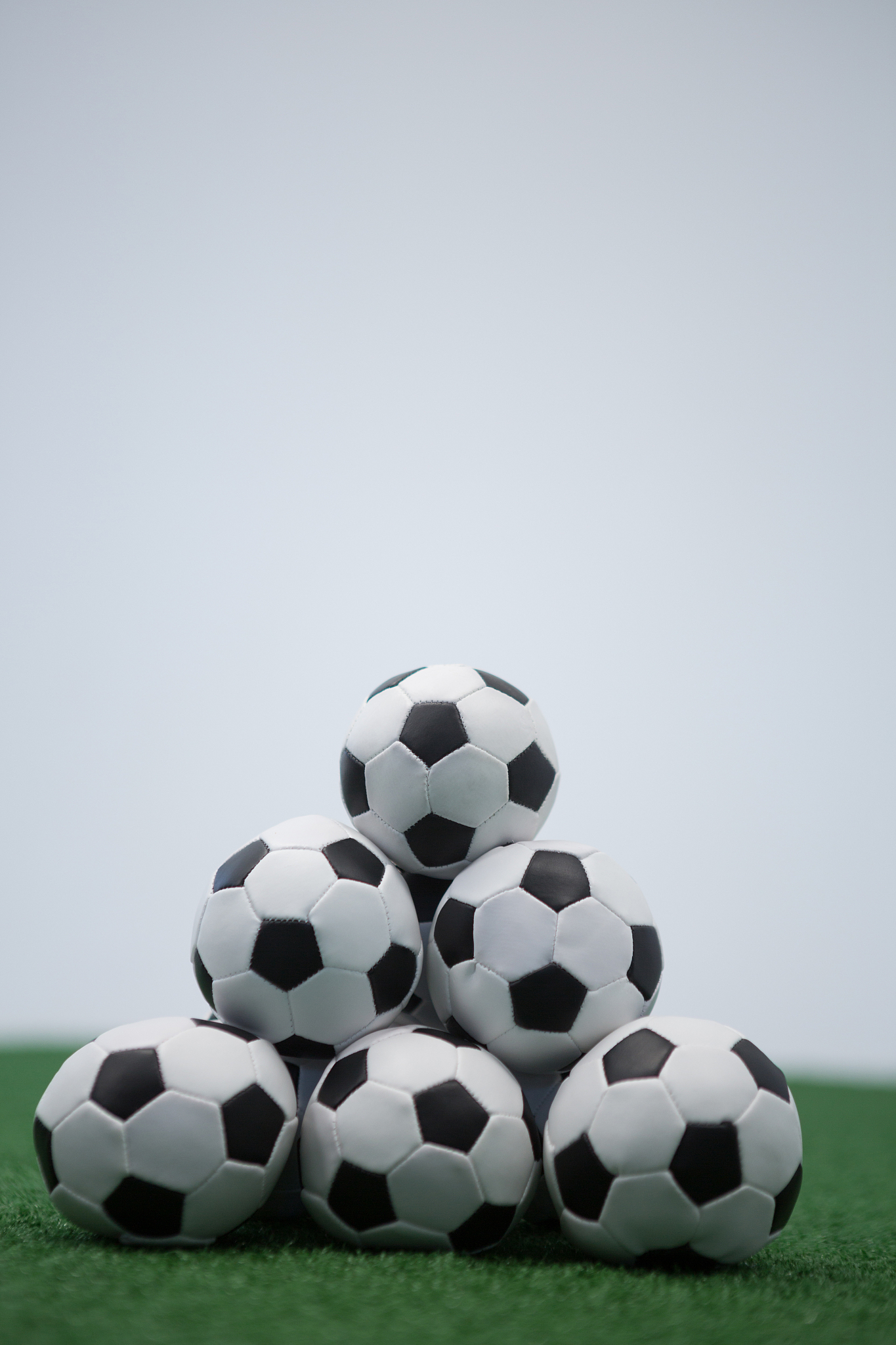 stack of piled up football soccer balls on artificial grass