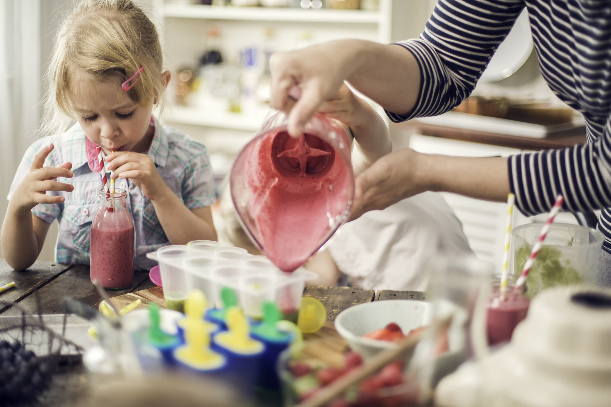 two little girls preparing popsicles from a smoothie