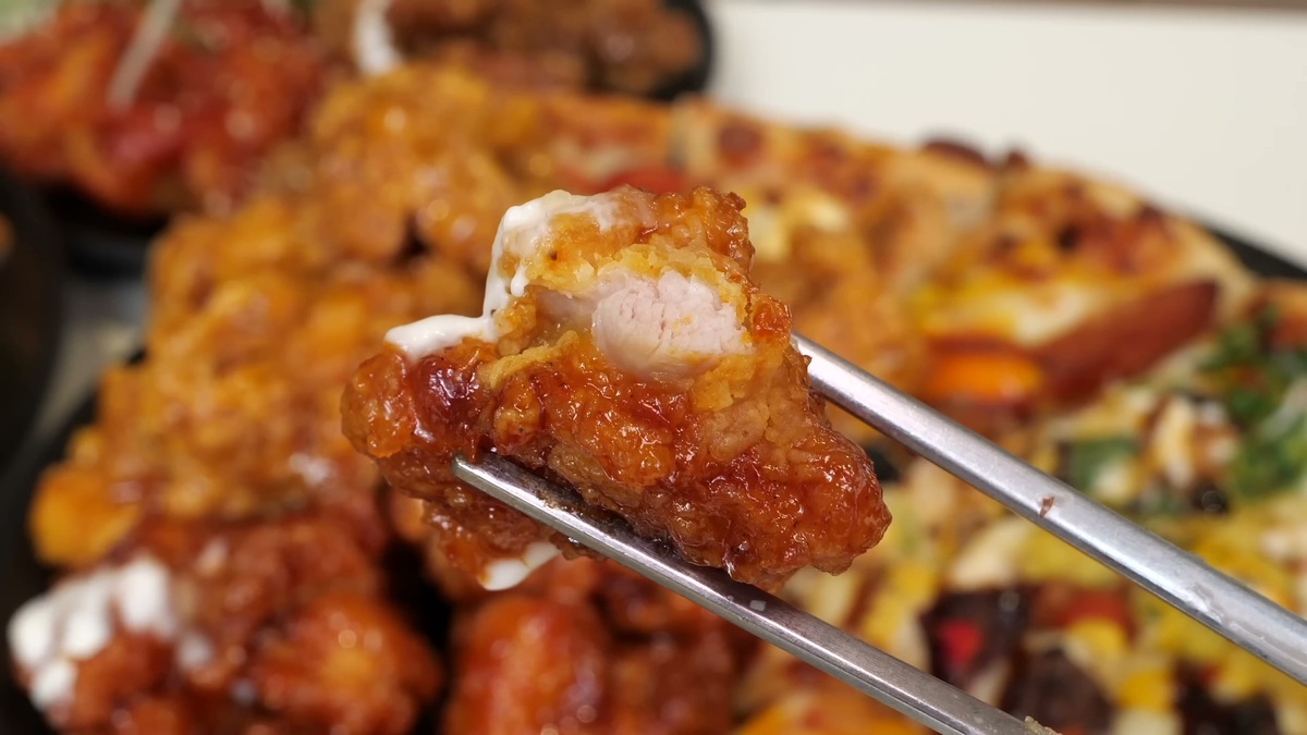 用金属筷子夹起金黄酥脆的炸鸡