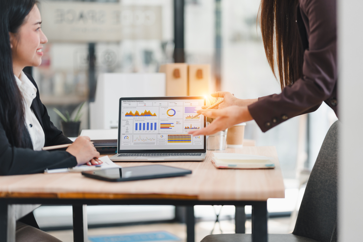 一位女商人在现代办公室环境中,向同事展示笔记本电脑