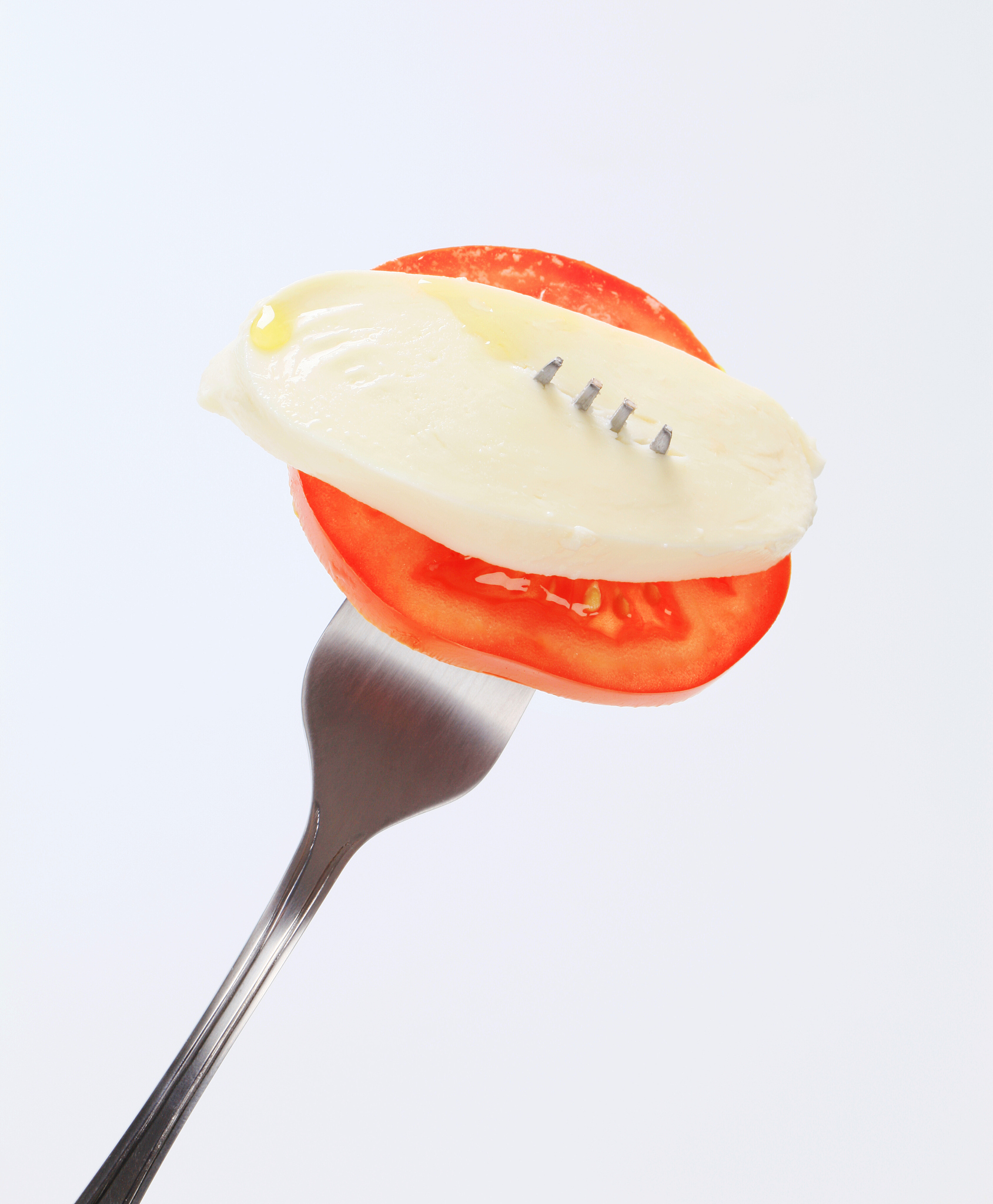 slice of mozzarella cheese and tomato on a fork