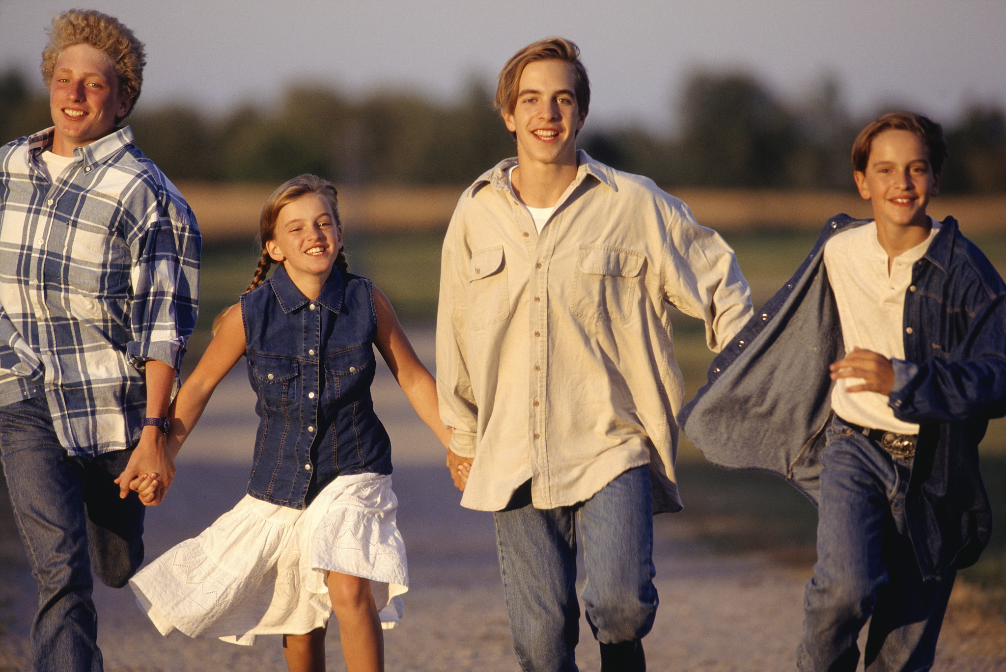 two teenage boys (13-14), girl (8-9) and boy (10-11) running on 