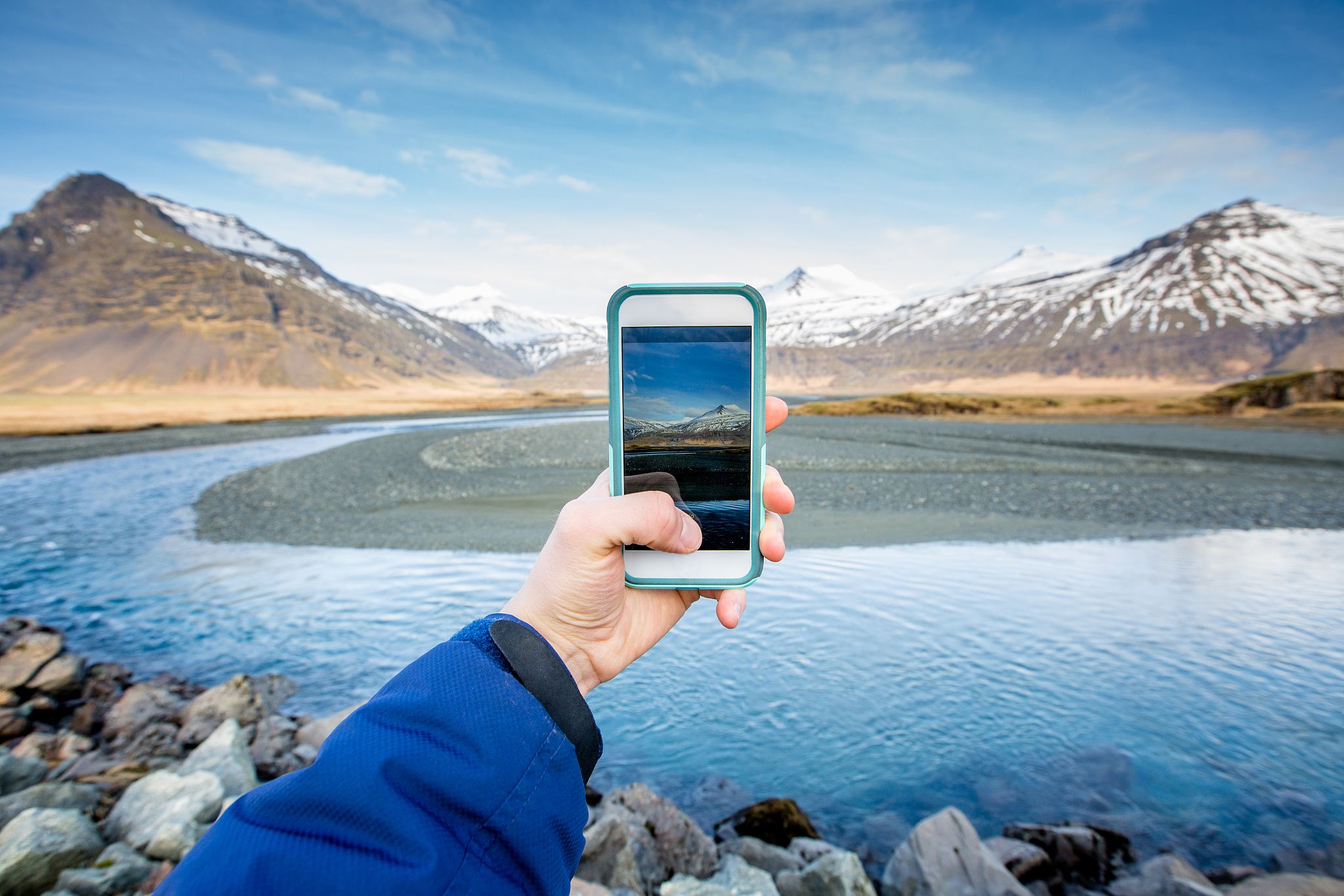 person's arm takes smart phone pic of landscape