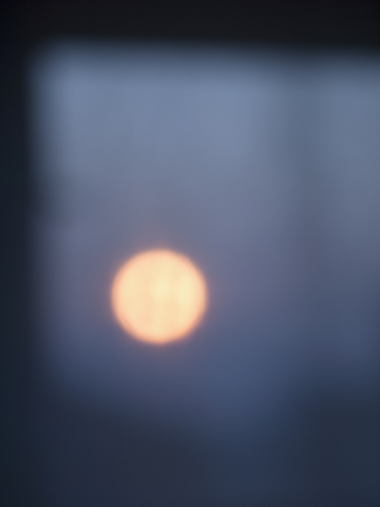 defocused image of sun seen through window during sunset