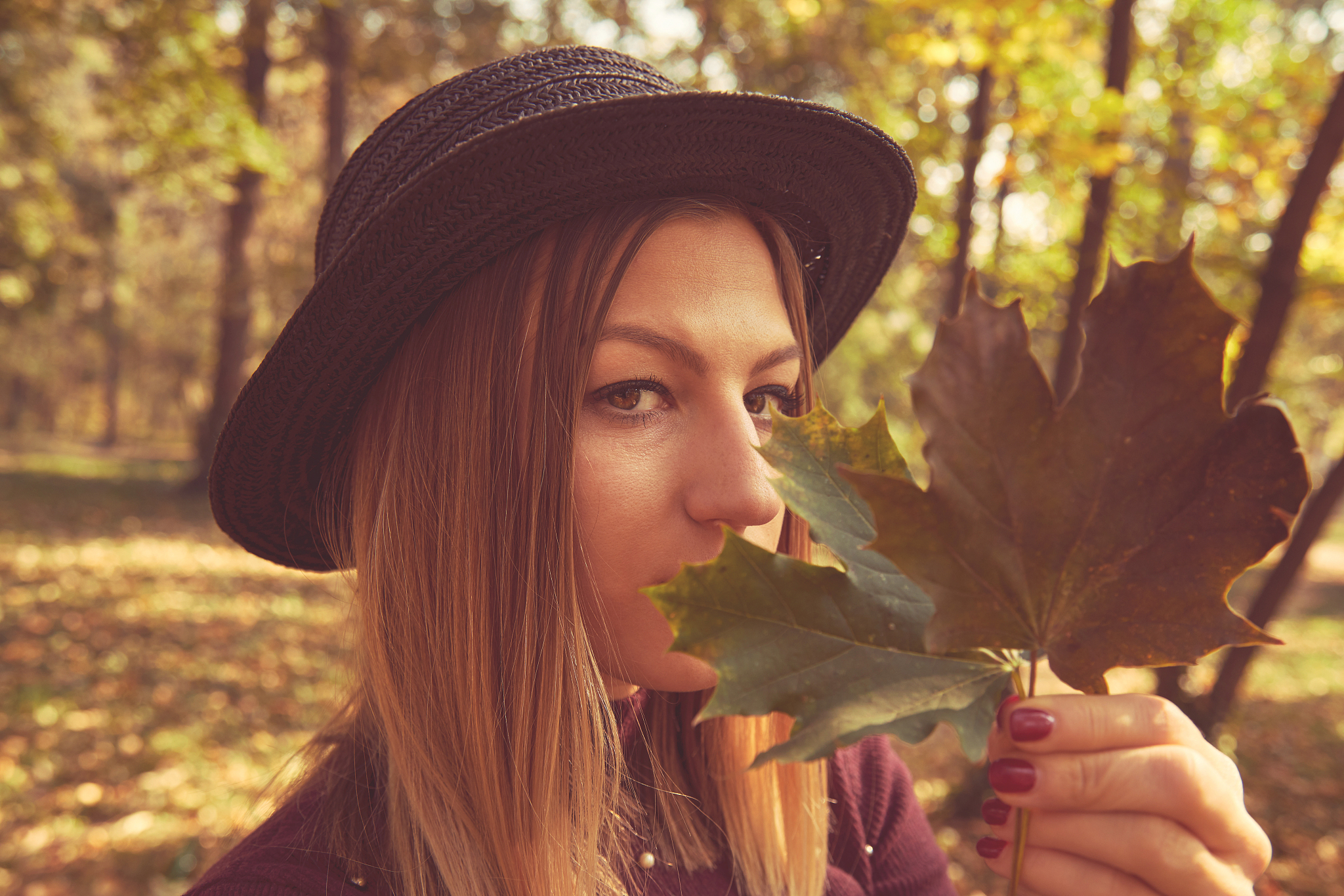 portrait of beautiful woman hiding behind autumn leaf. autumn co
