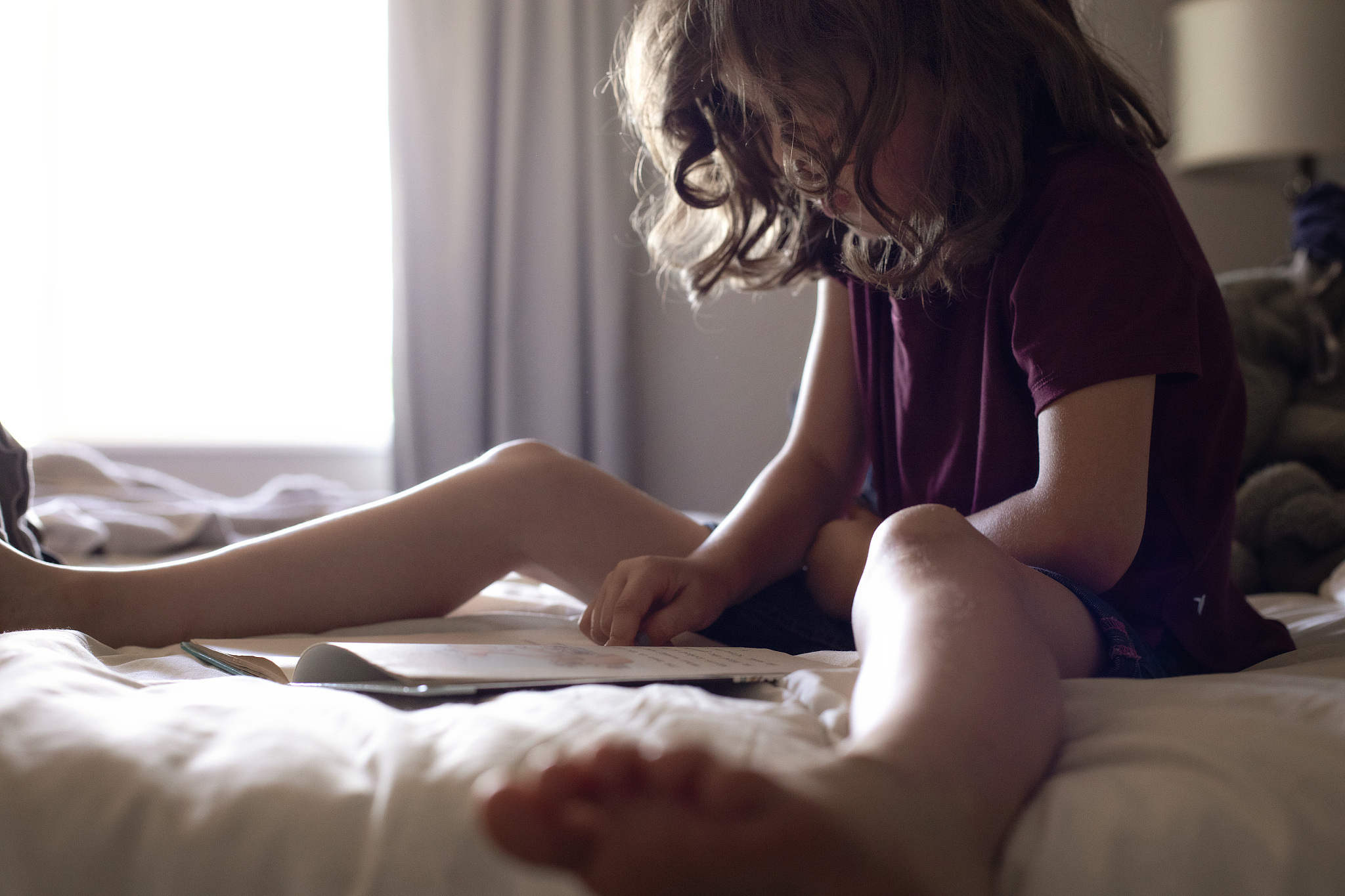girl reading book on bed