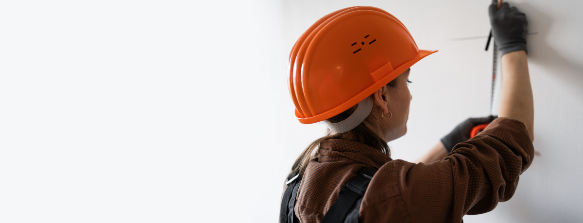 戴着安全帽的建筑师用钢尺测量墙壁.建筑和家居装修
