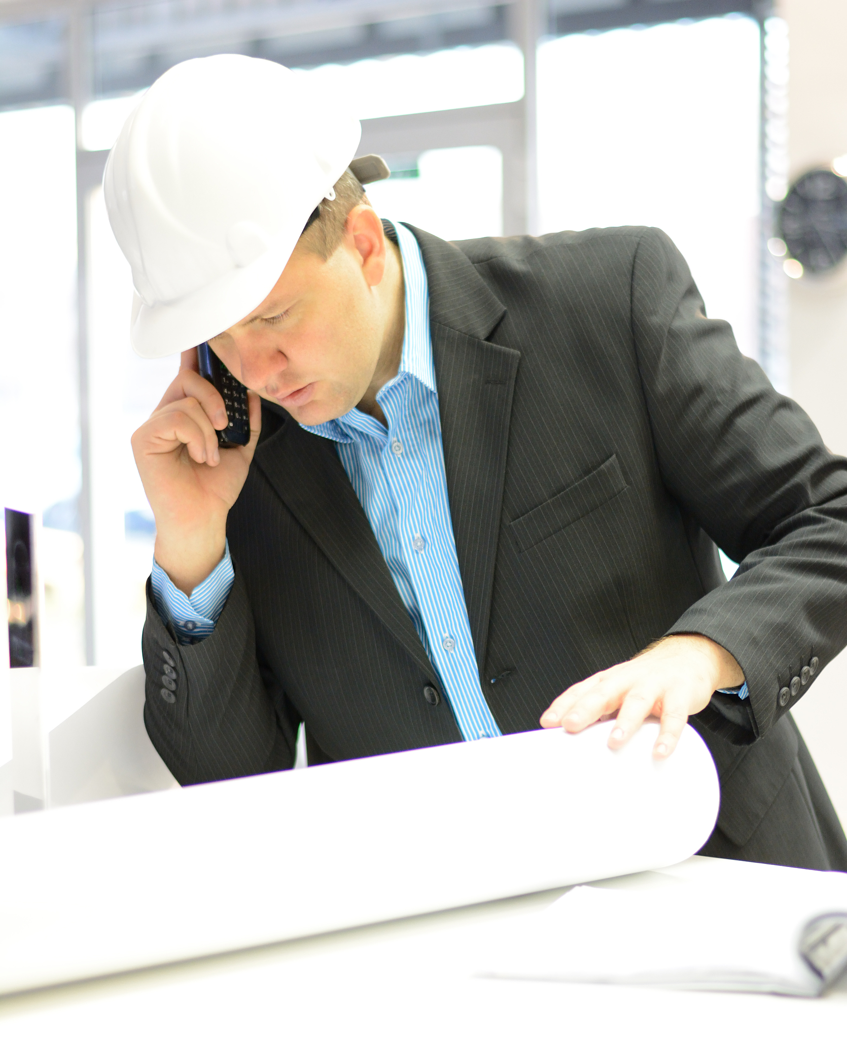 architect with hardhat and blueprints at workplace