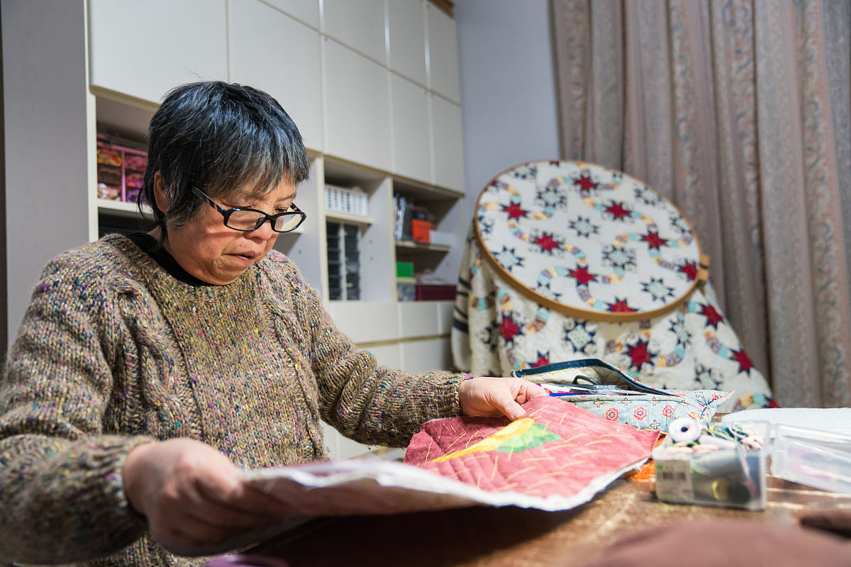 一位年长妇女在她的家中缝纫和制作工艺品
