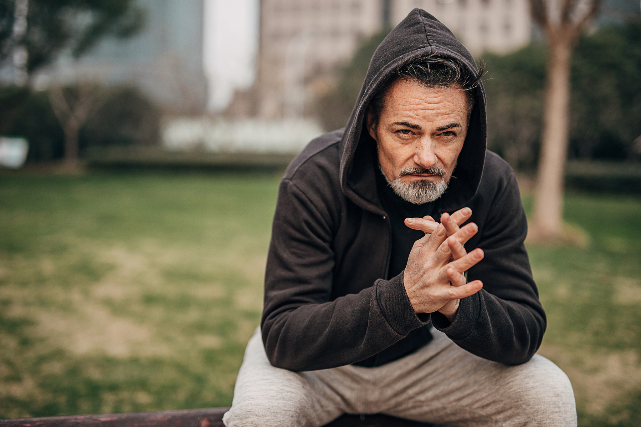 one mature man sitting on the bench in public park