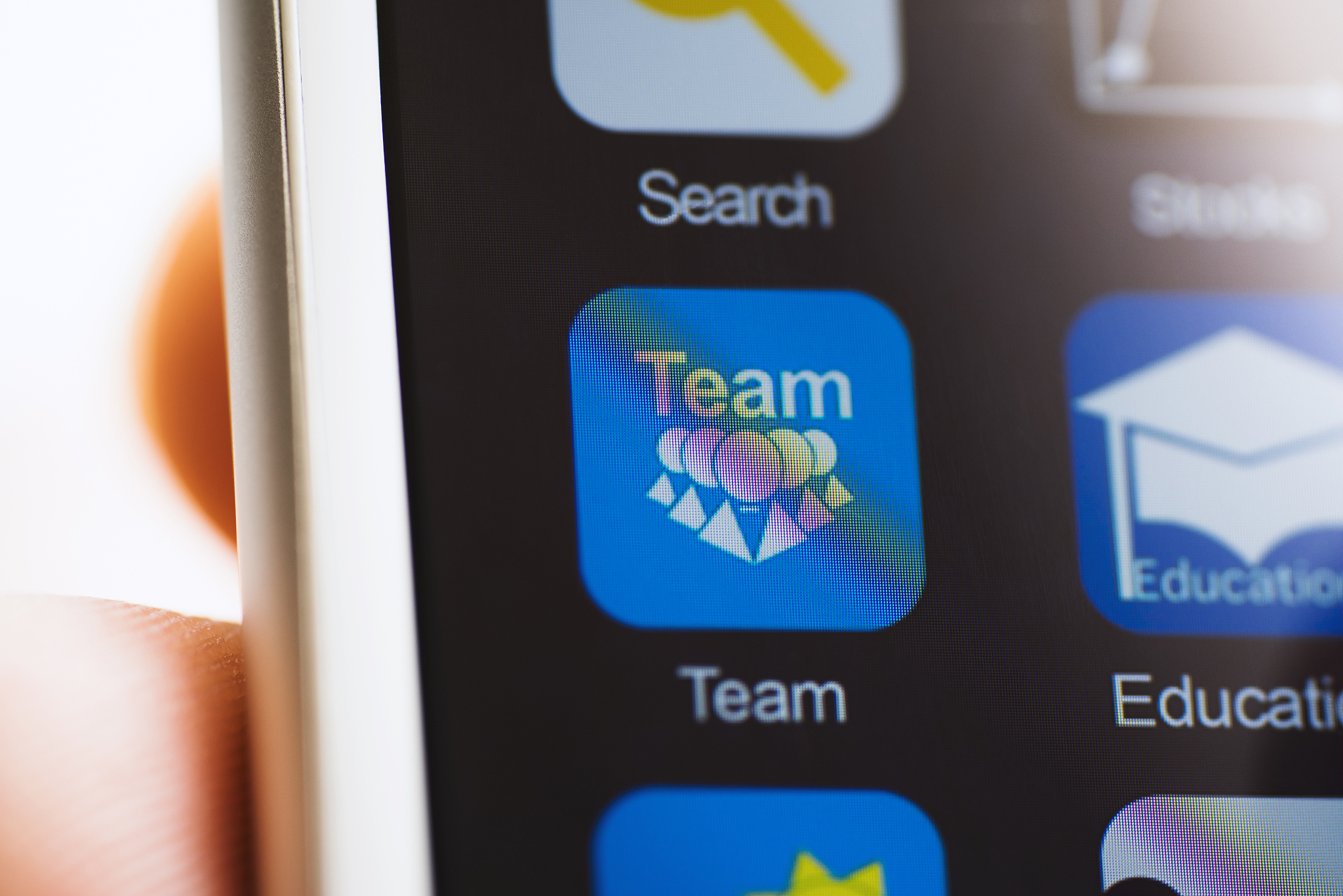 hand holding phone, team app icon on screen